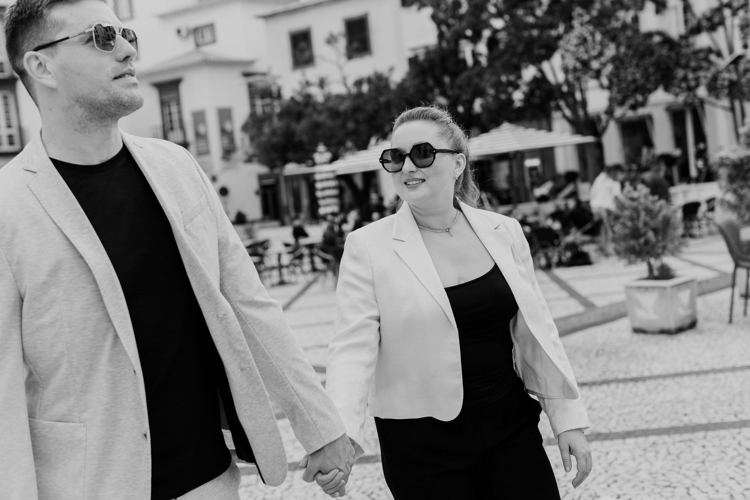 Black and white close crop of couple holding hands walking through Funchal Old Town, cobblestones underfoot, Madeira