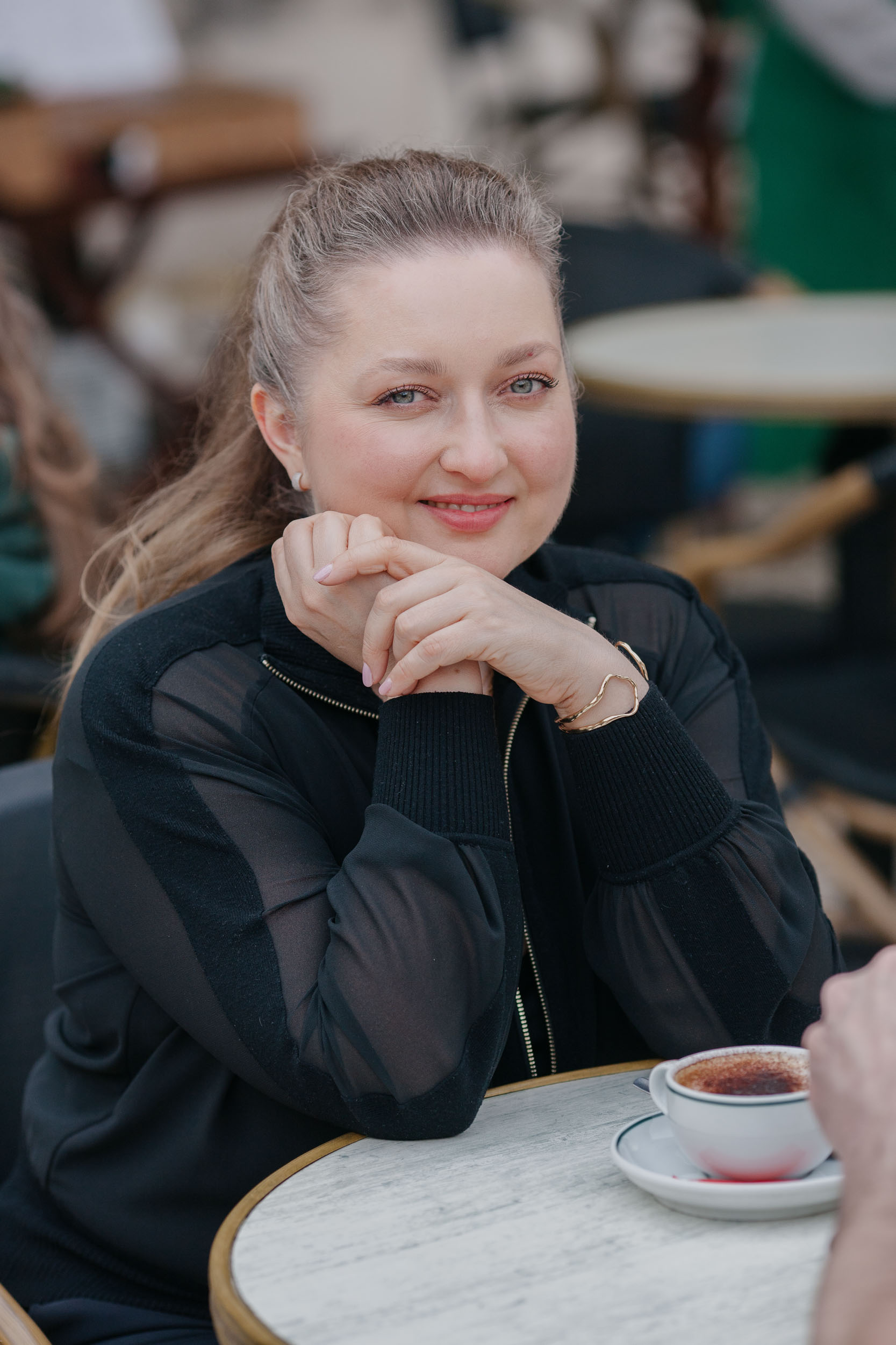 Solo portrait of Olga at a cafe table, casual outfit, warm interior light, Funchal, Madeira