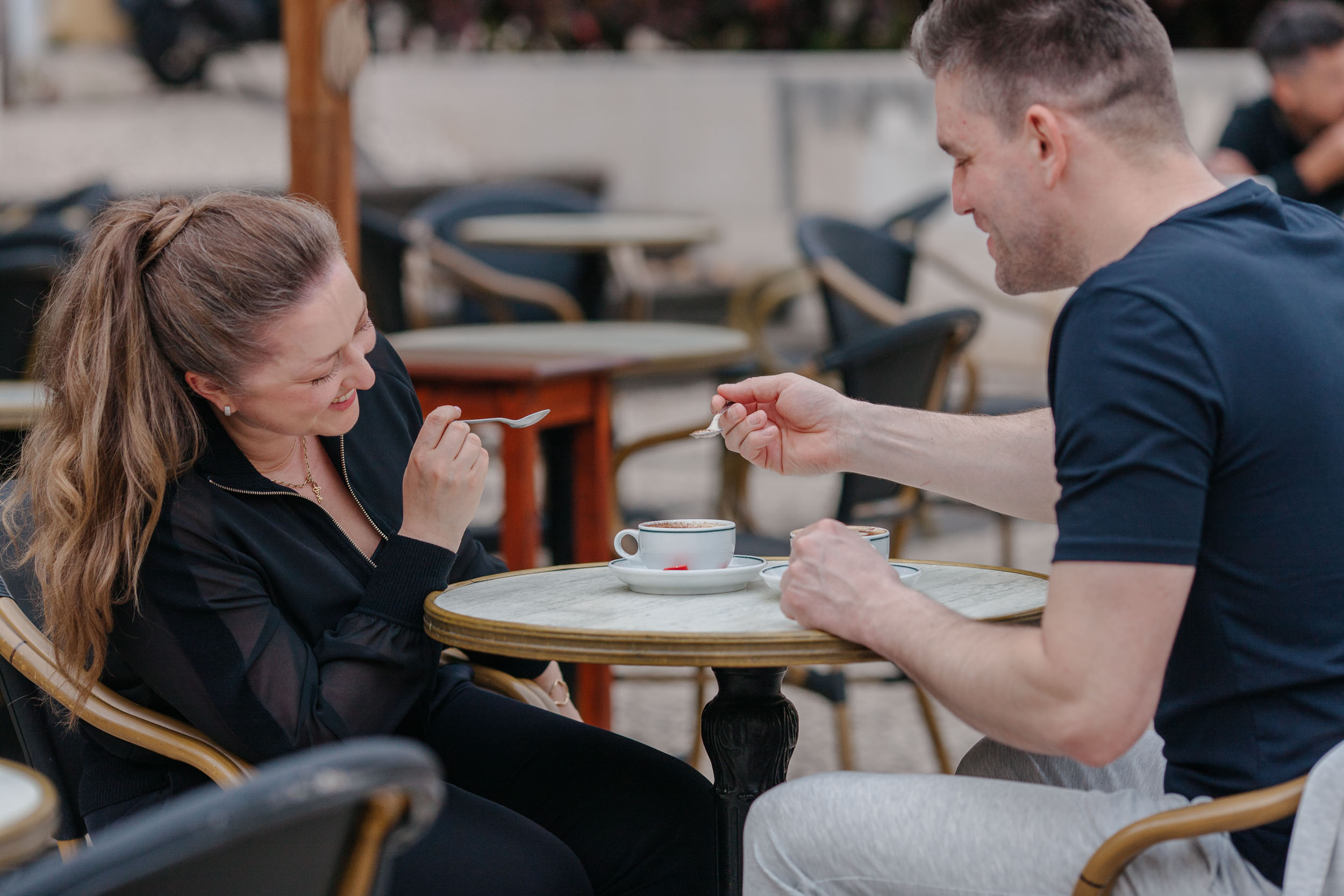 Man reaching toward woman's face at cafe table, intimate moment, Funchal, Madeira