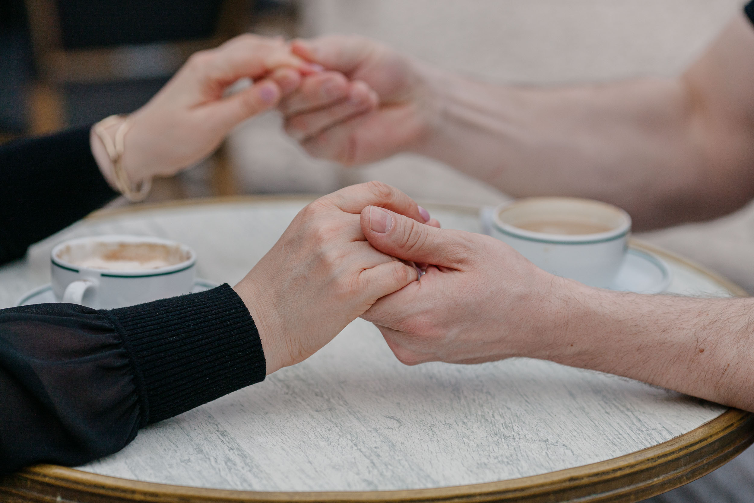 Couple holding hands across a marble cafe table, close detail shot, Funchal, Madeira