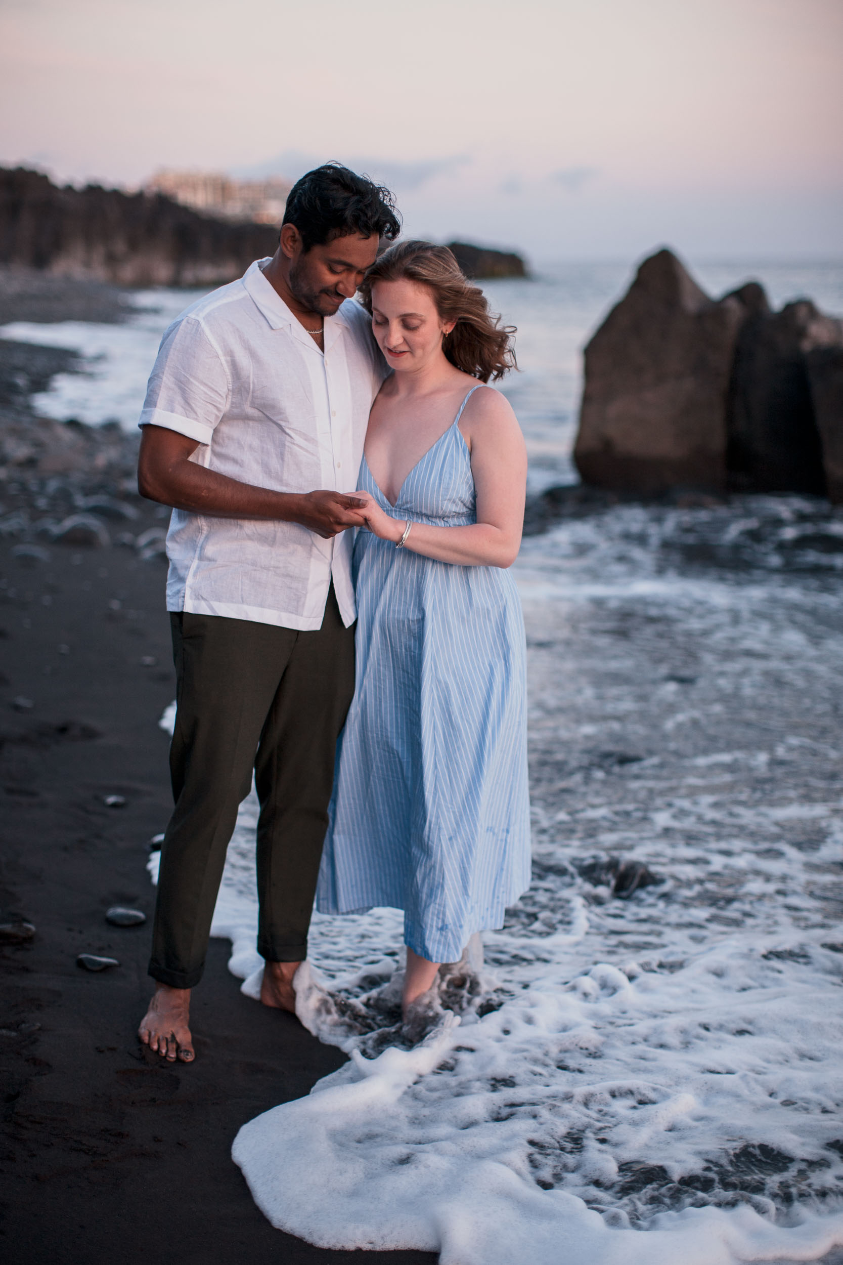 Couple wading in ocean shallows at dusk, Praia Formosa, Madeira