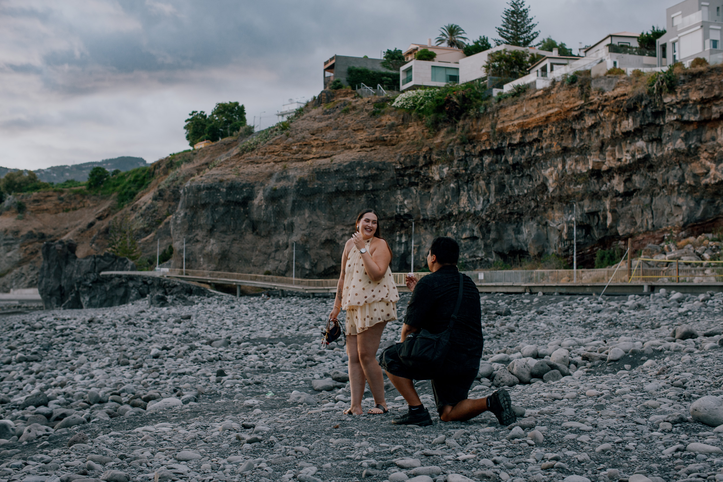 Carlos on one knee proposing on the pebble beach below the cliff at Praia Formosa, Madeira
