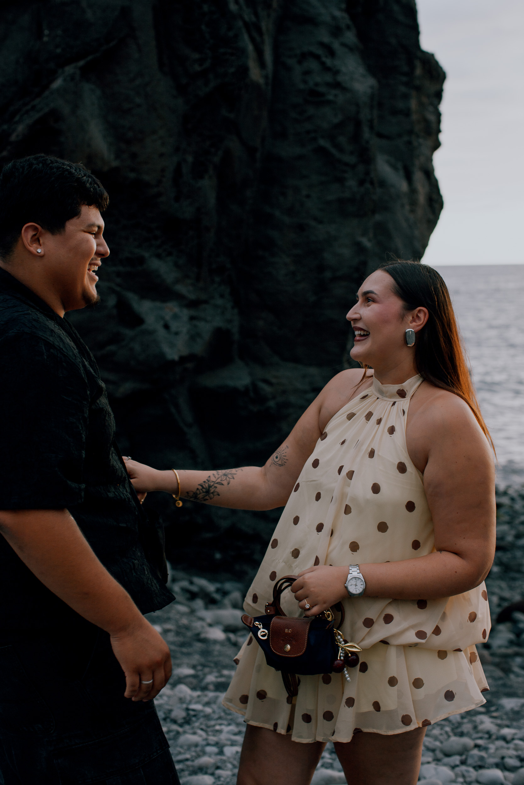 Just engaged and laughing together under the dark volcanic rock at Praia Formosa, Madeira