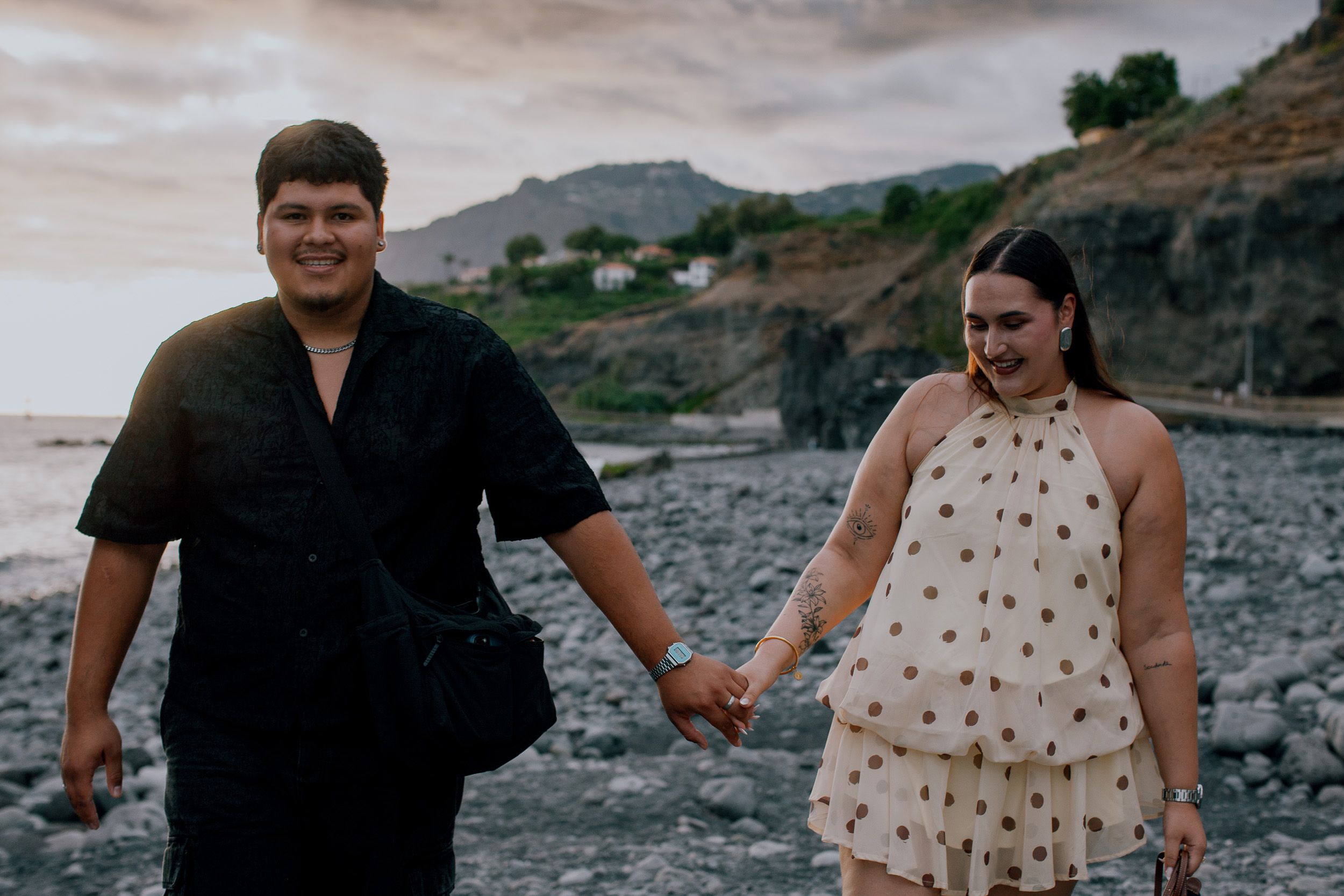 Walking hand in hand along the stony beach after the proposal, Funchal coast, Madeira