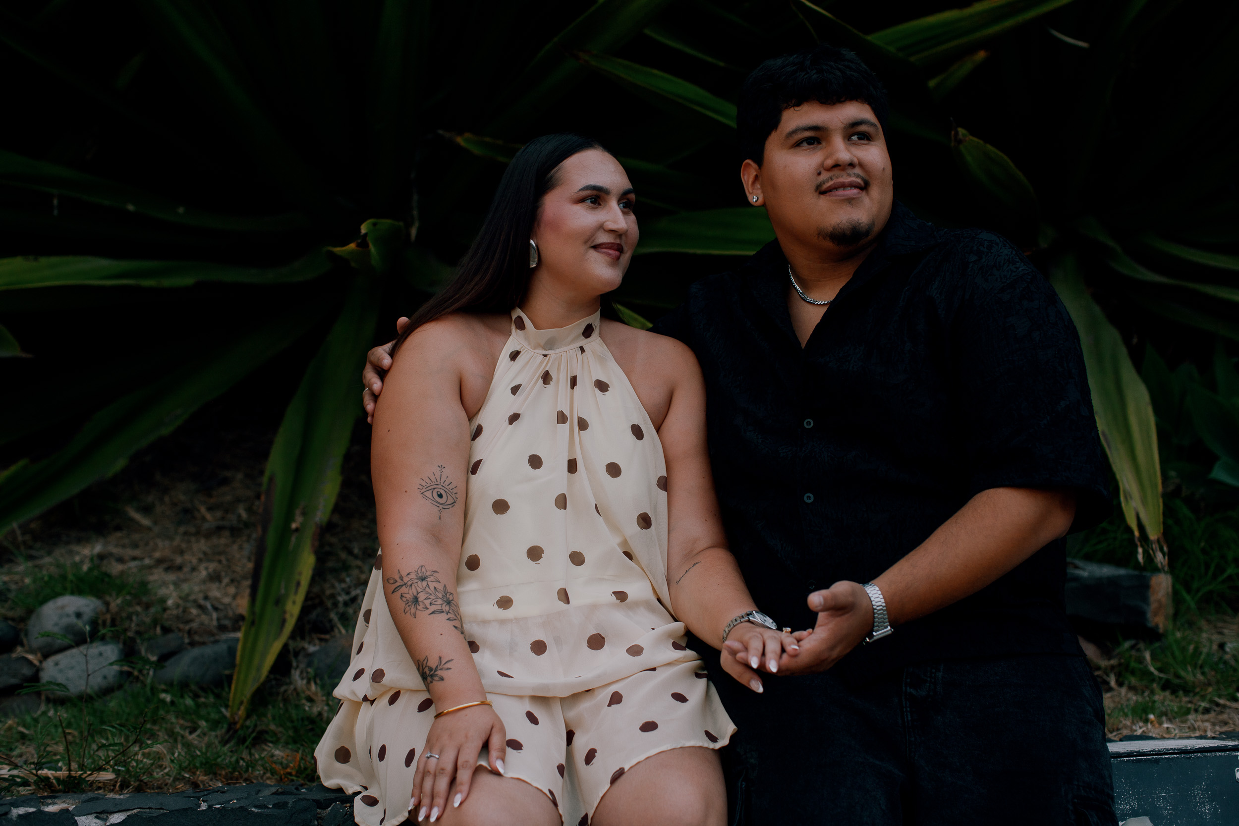 Sitting together against the green leaves at the edge of the beach, engaged couple on Madeira