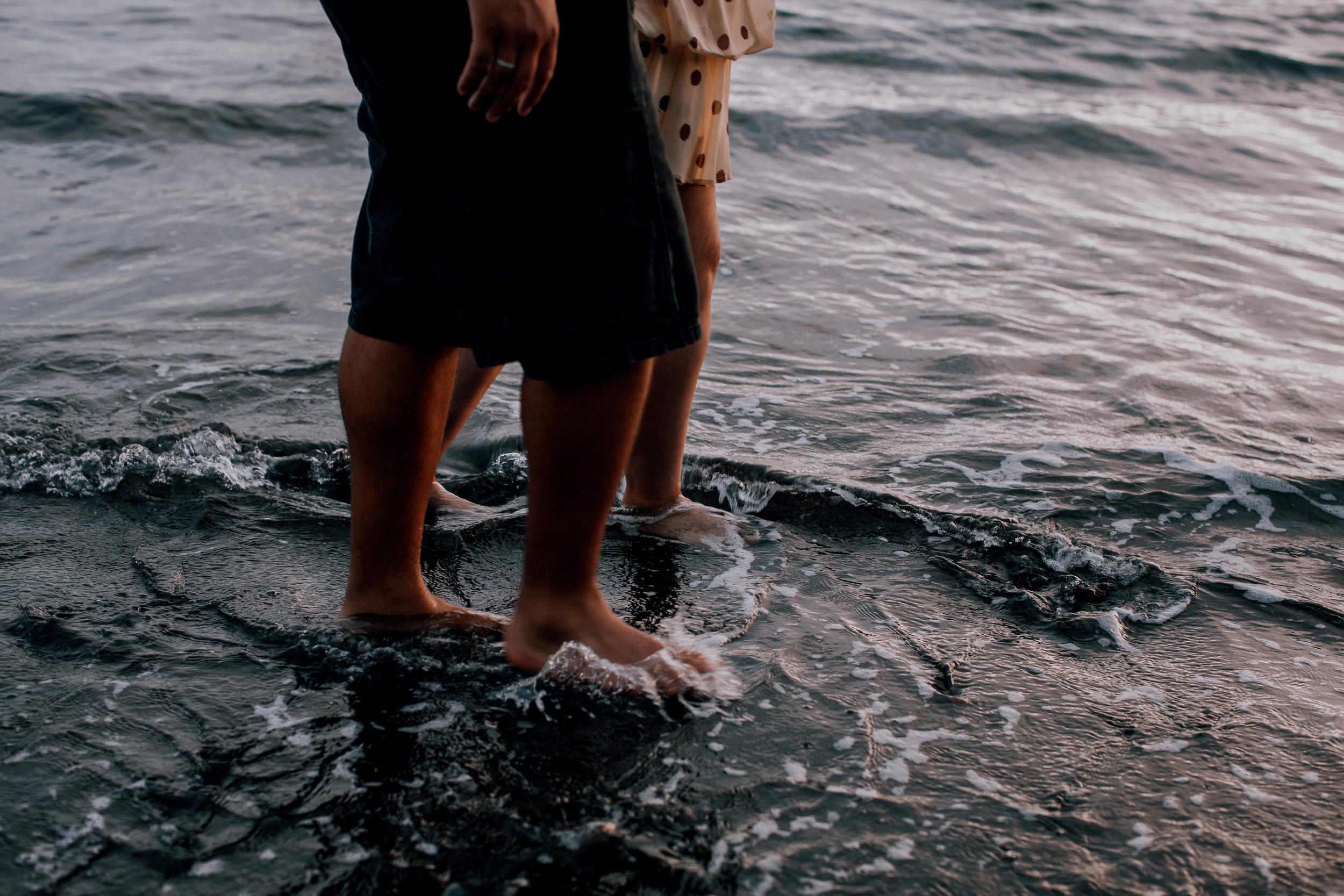 Bare feet in the surf on the dark pebbles at dusk, Praia Formosa, Madeira