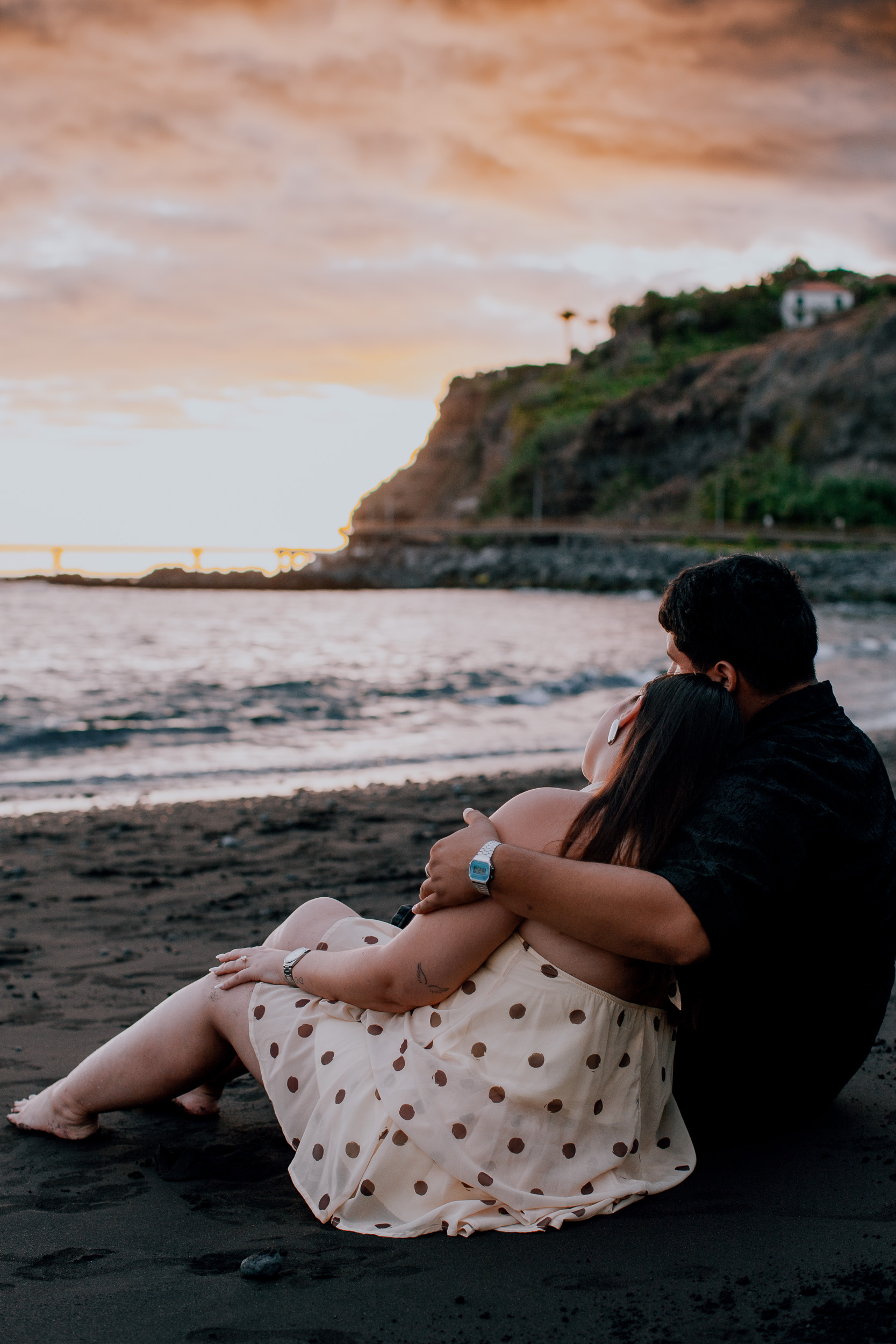 Sitting on the sand watching the pink sunset over the Funchal coast, Madeira