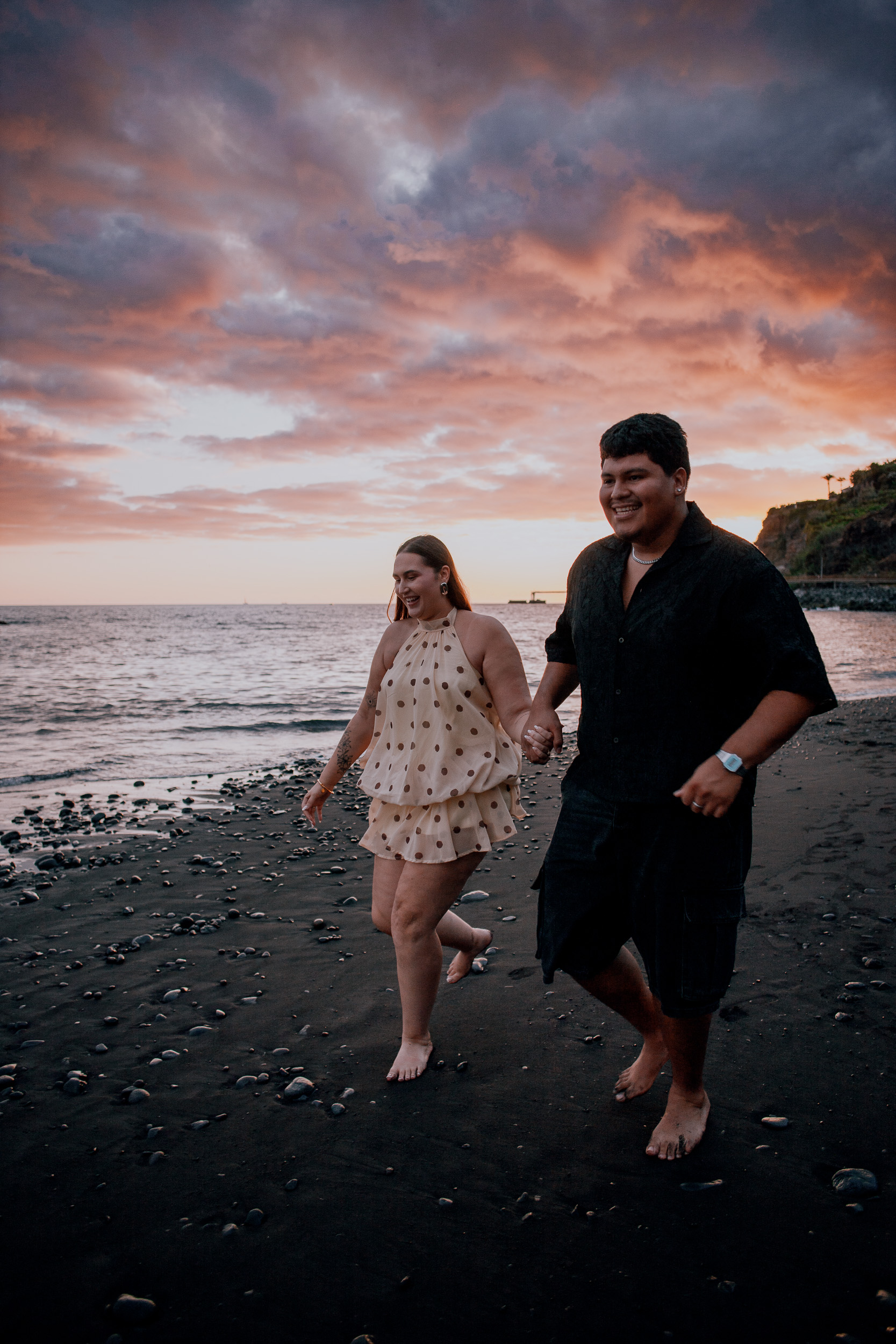 Running along the waterline under pink sunset clouds, engagement at Praia Formosa, Madeira