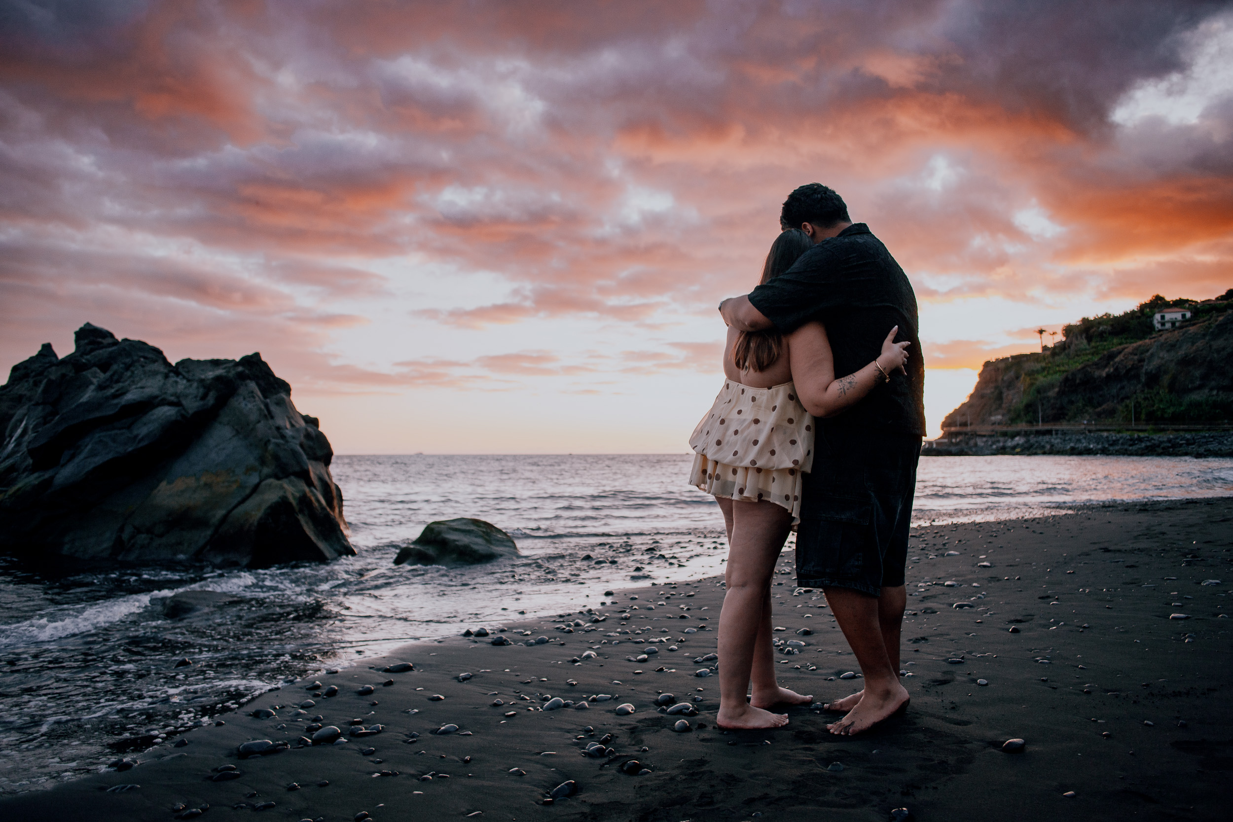 Kissing beside the rock as the sunset peaks over Praia Formosa, Madeira