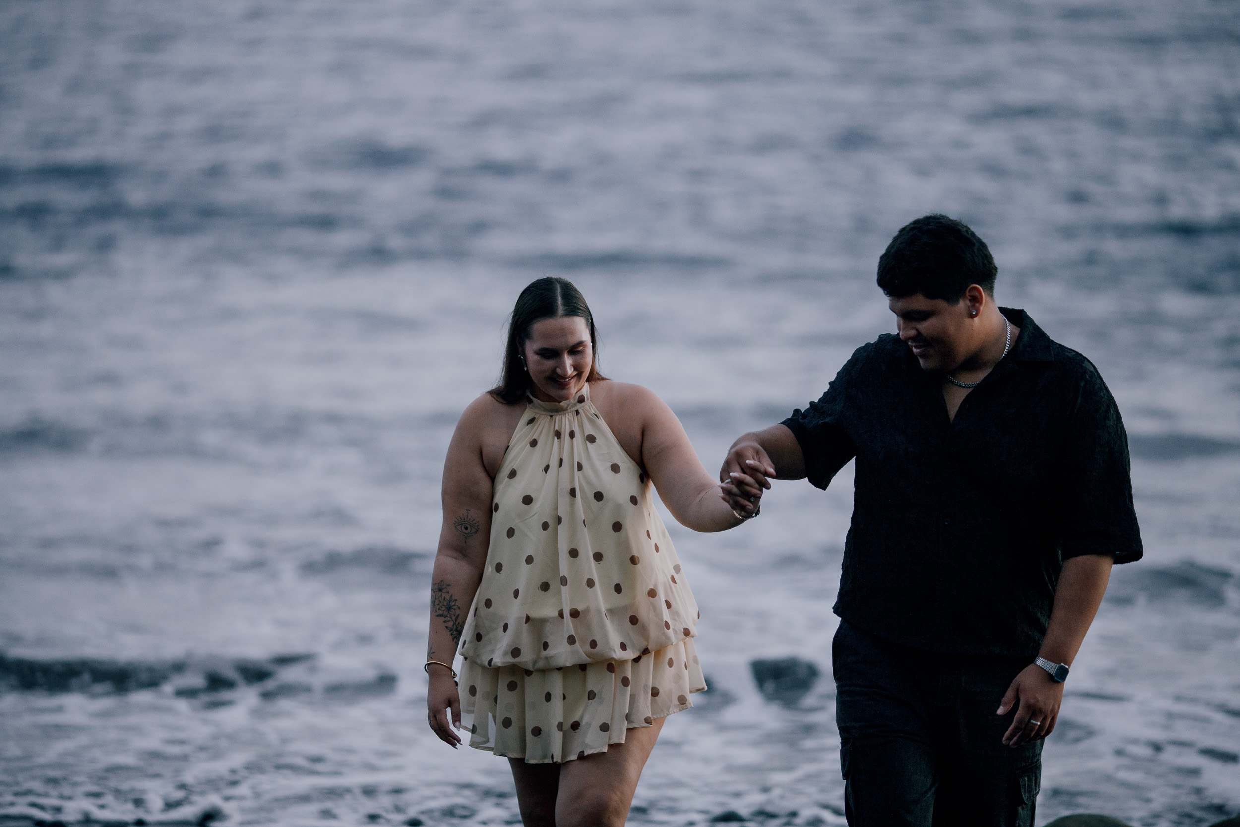 He leads her by the hand through the shallow water at dusk, Madeira
