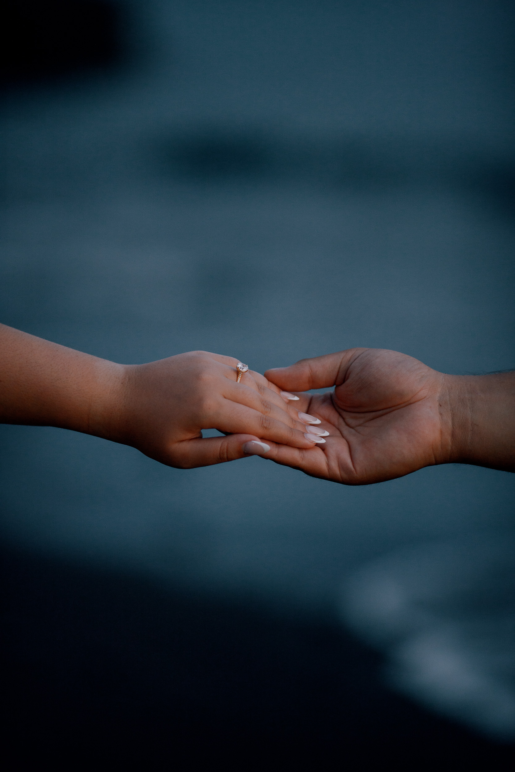 Her hand with the engagement ring resting on his palm in the dark, Madeira