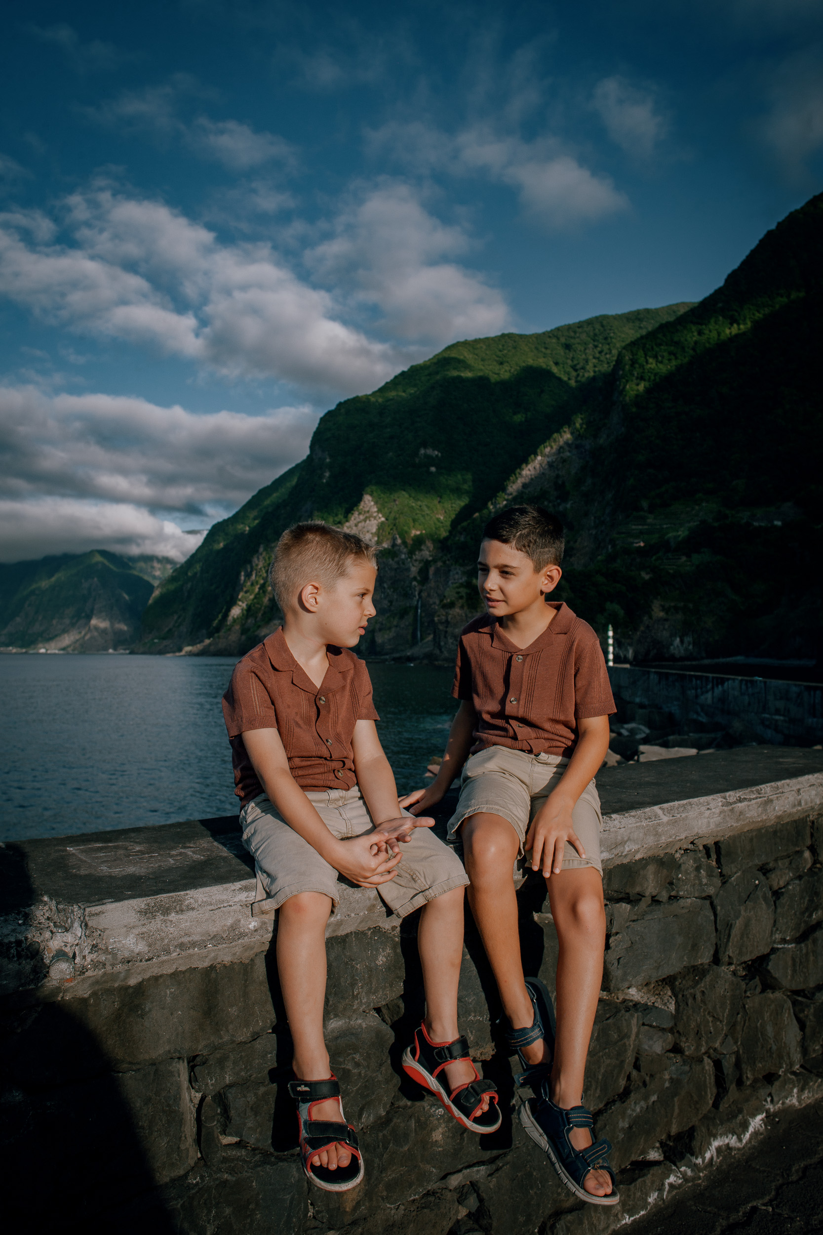 Two brothers sitting on the stone wall above the bay at Seixal, Madeira