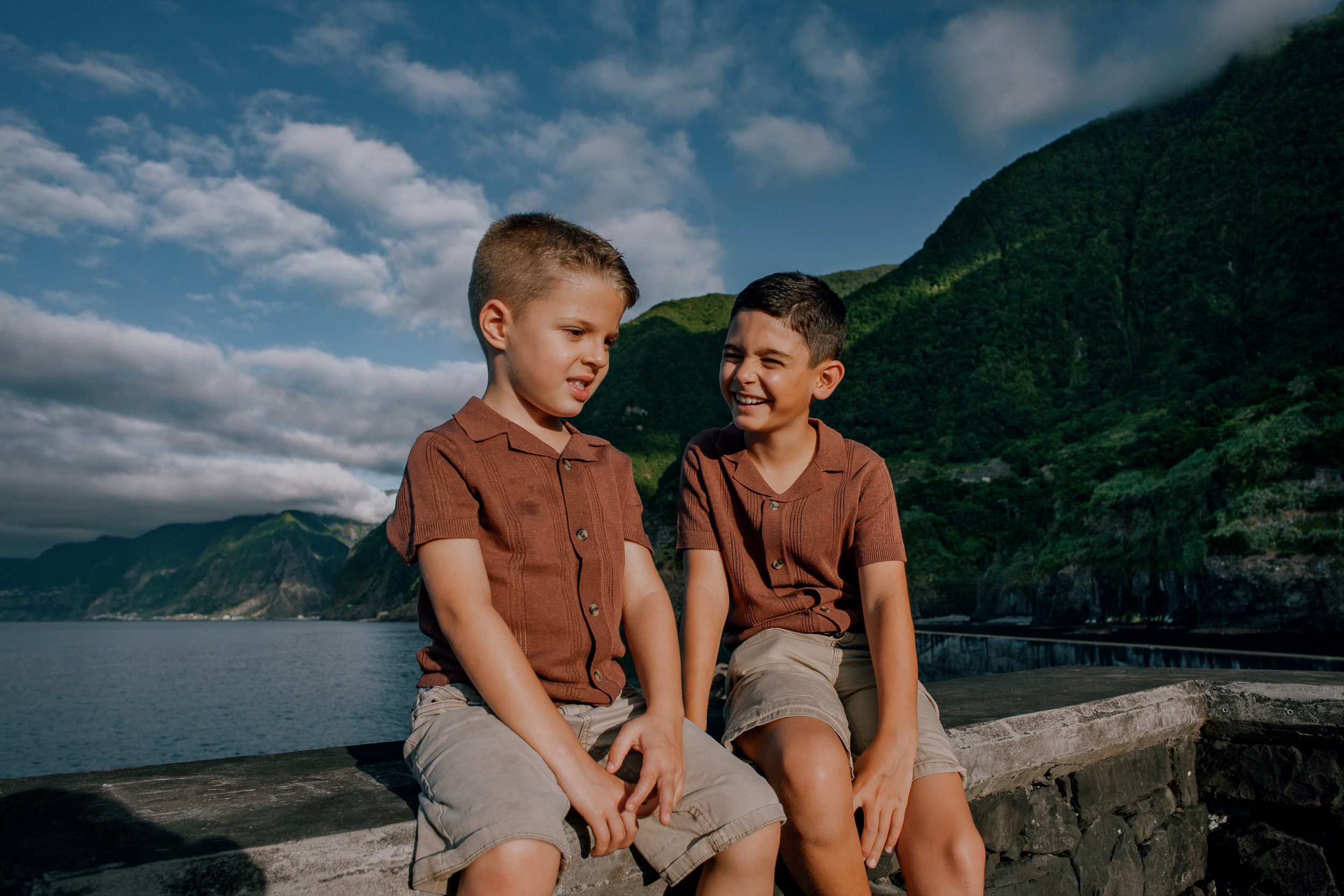 Brothers laughing together on the stone parapet, Seixal Beach, Madeira