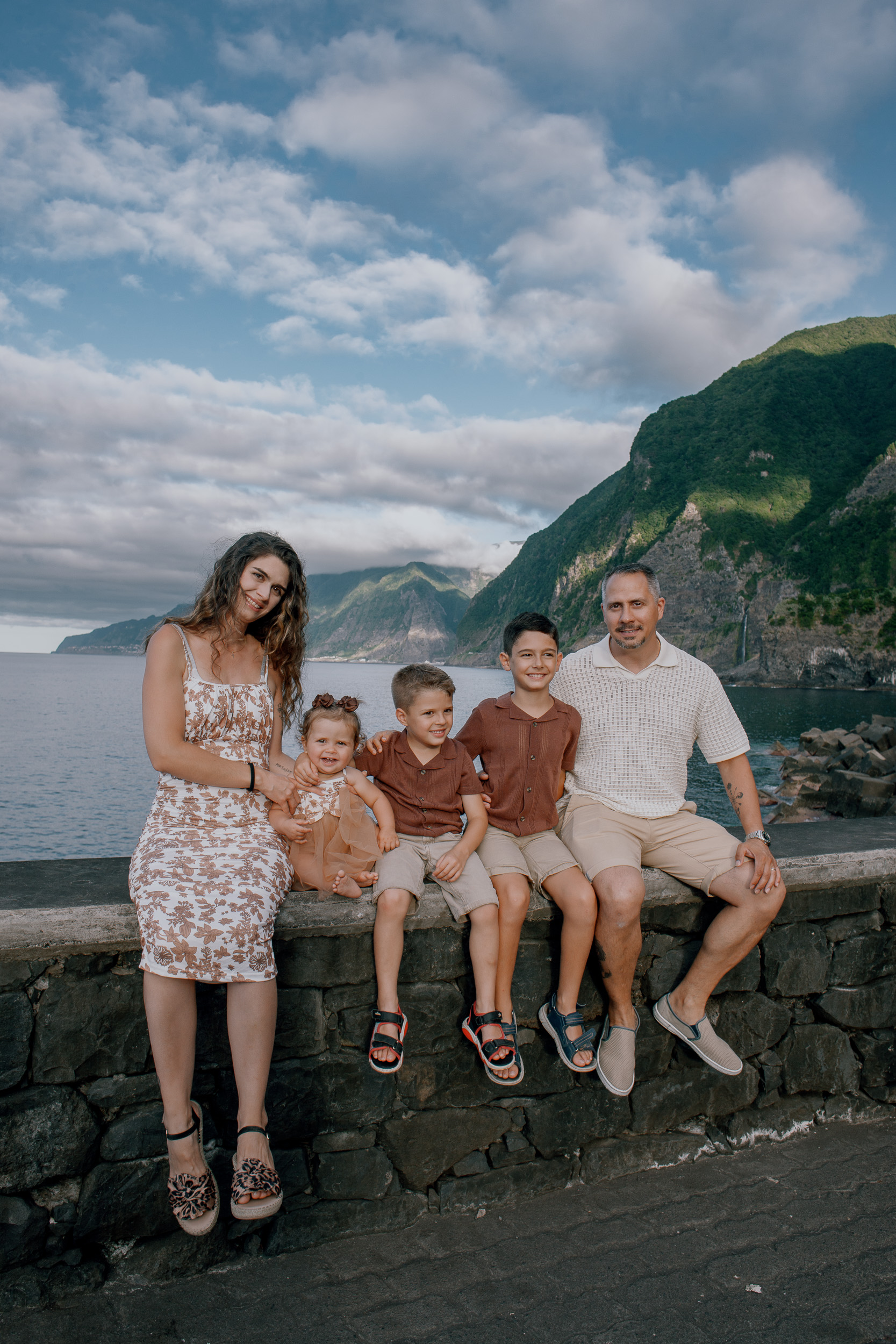 Family of five seated on the stone wall above the bay, Seixal, Madeira
