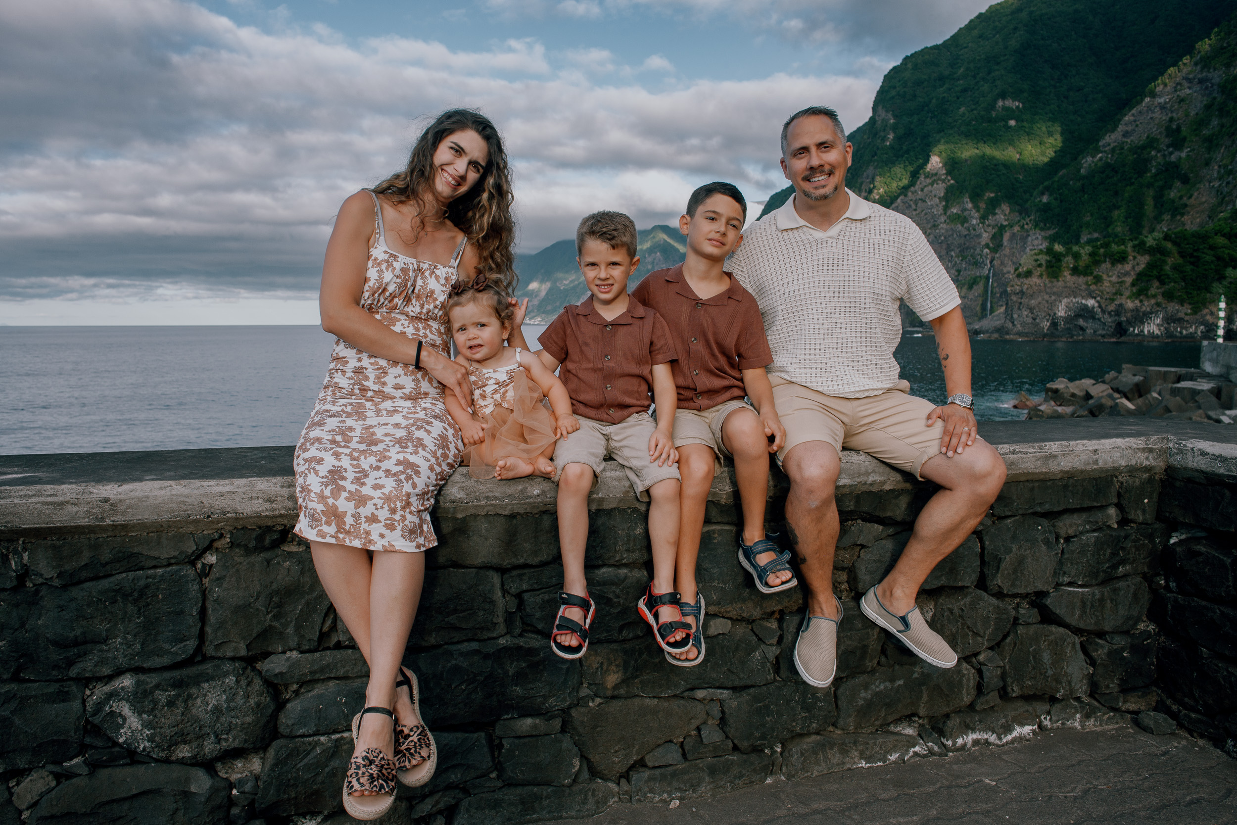 Parents and three kids lined up on the seawall, Seixal Beach, Madeira