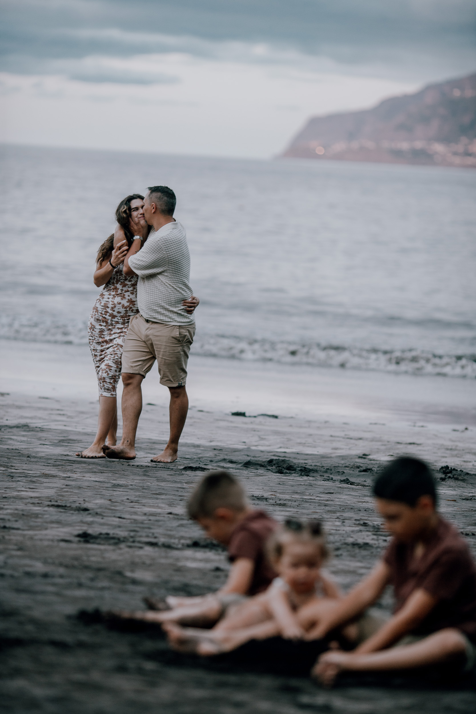 Parents kissing at the shore while the kids play in the sand, Seixal, Madeira