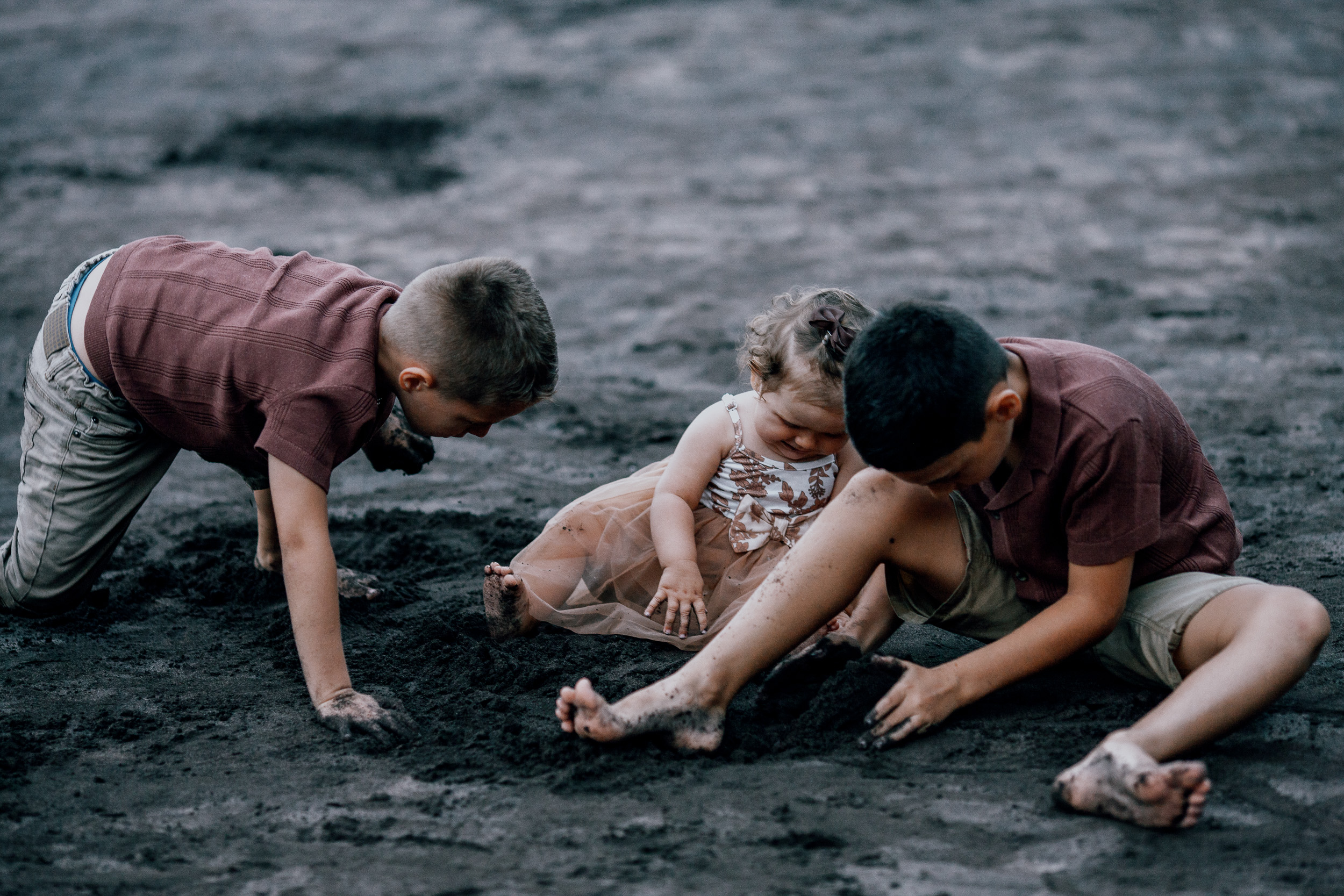 The boys and their sister digging in the black sand together, Seixal, Madeira