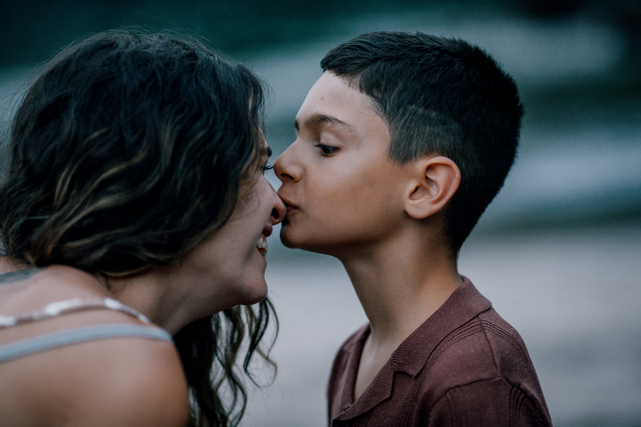 Mum kissing the older boy's cheek at dusk, Seixal Beach, Madeira