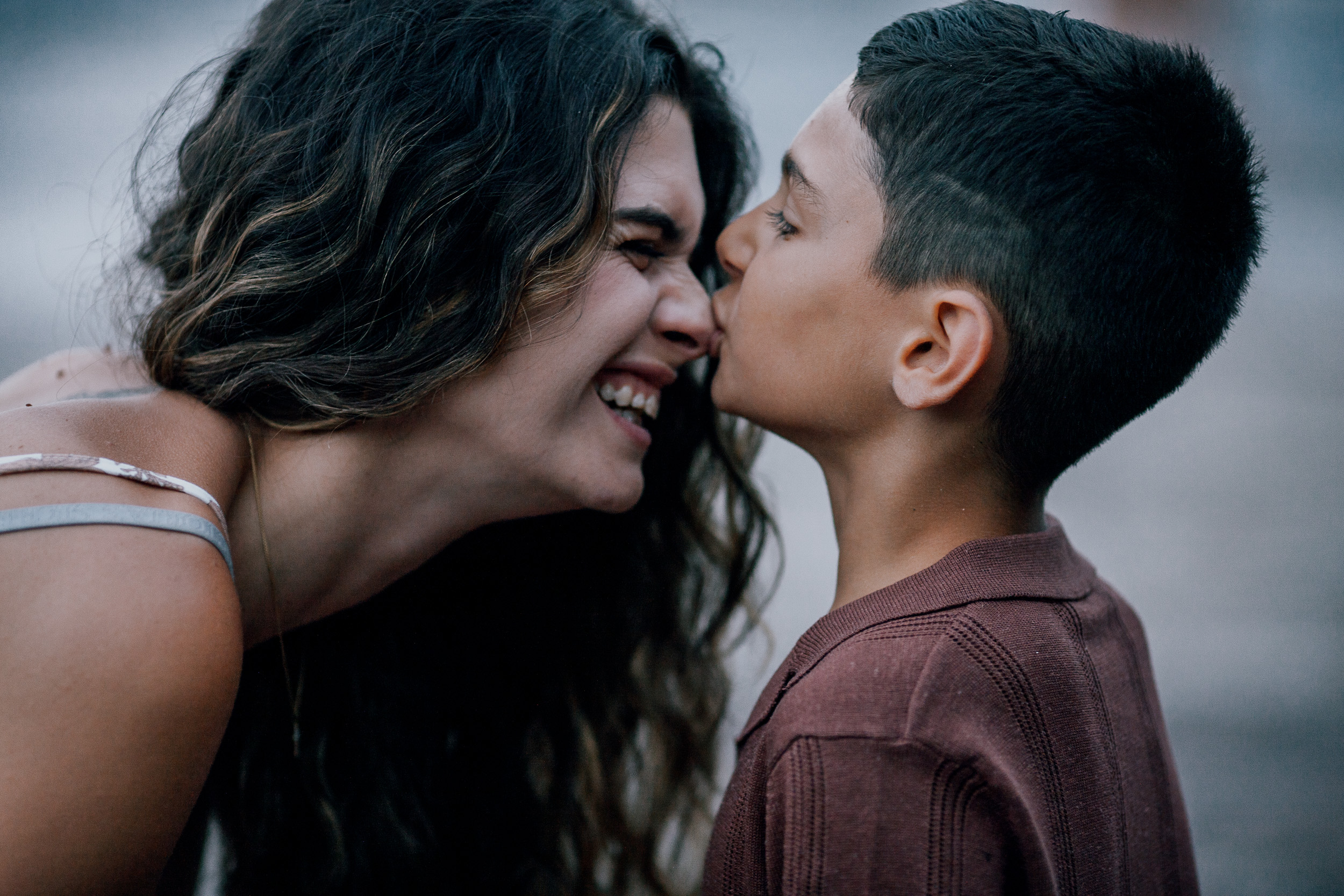 The son kissing his mother's cheek, both grinning, Seixal, Madeira