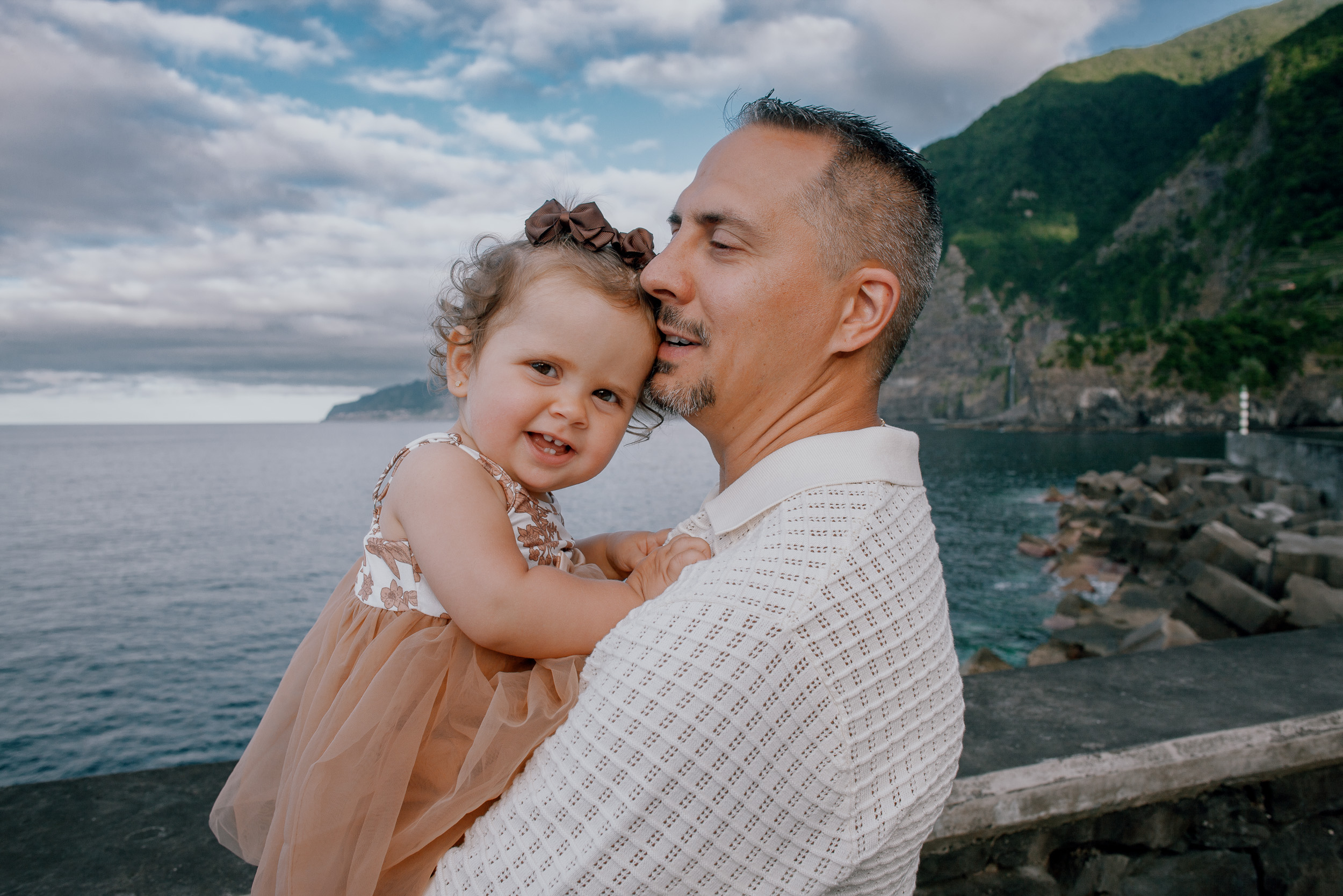 Father holding his daughter close by the sea wall, Seixal Beach, Madeira