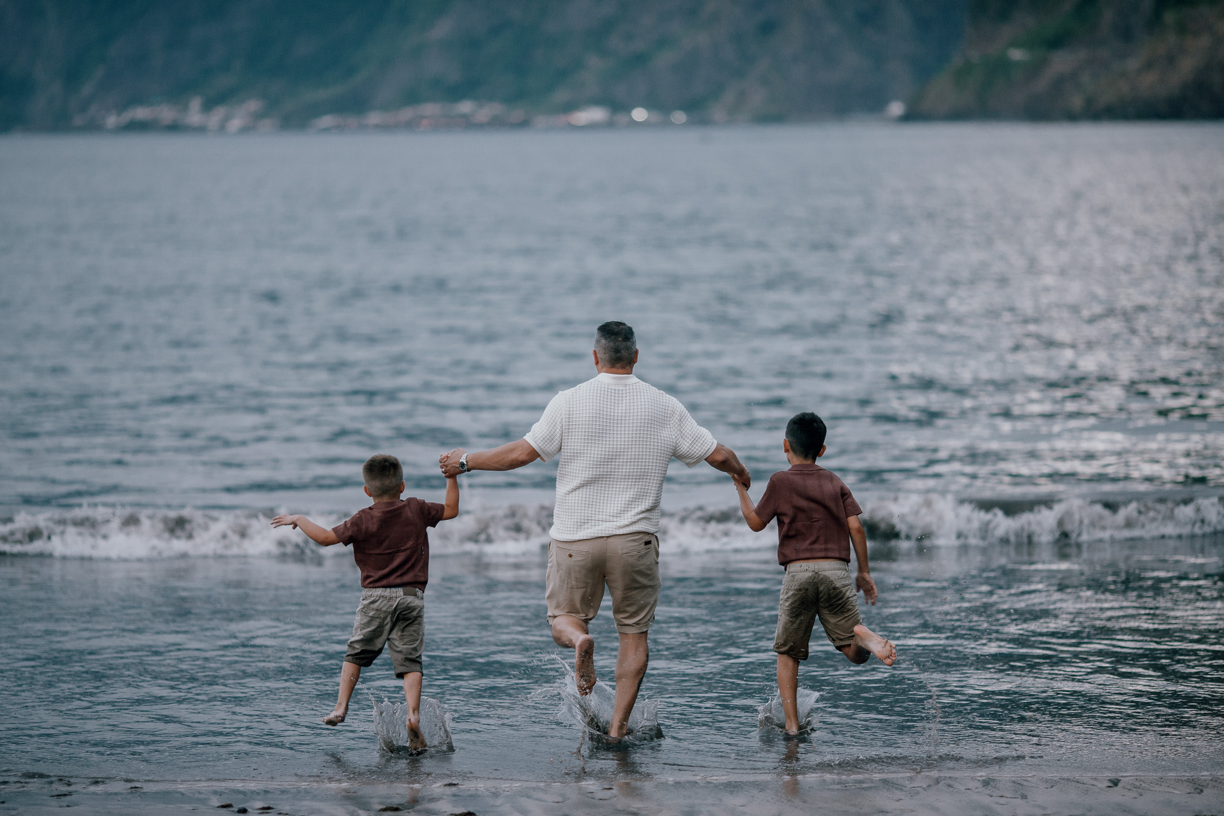 Father walking the shore with his running son, Seixal, Madeira