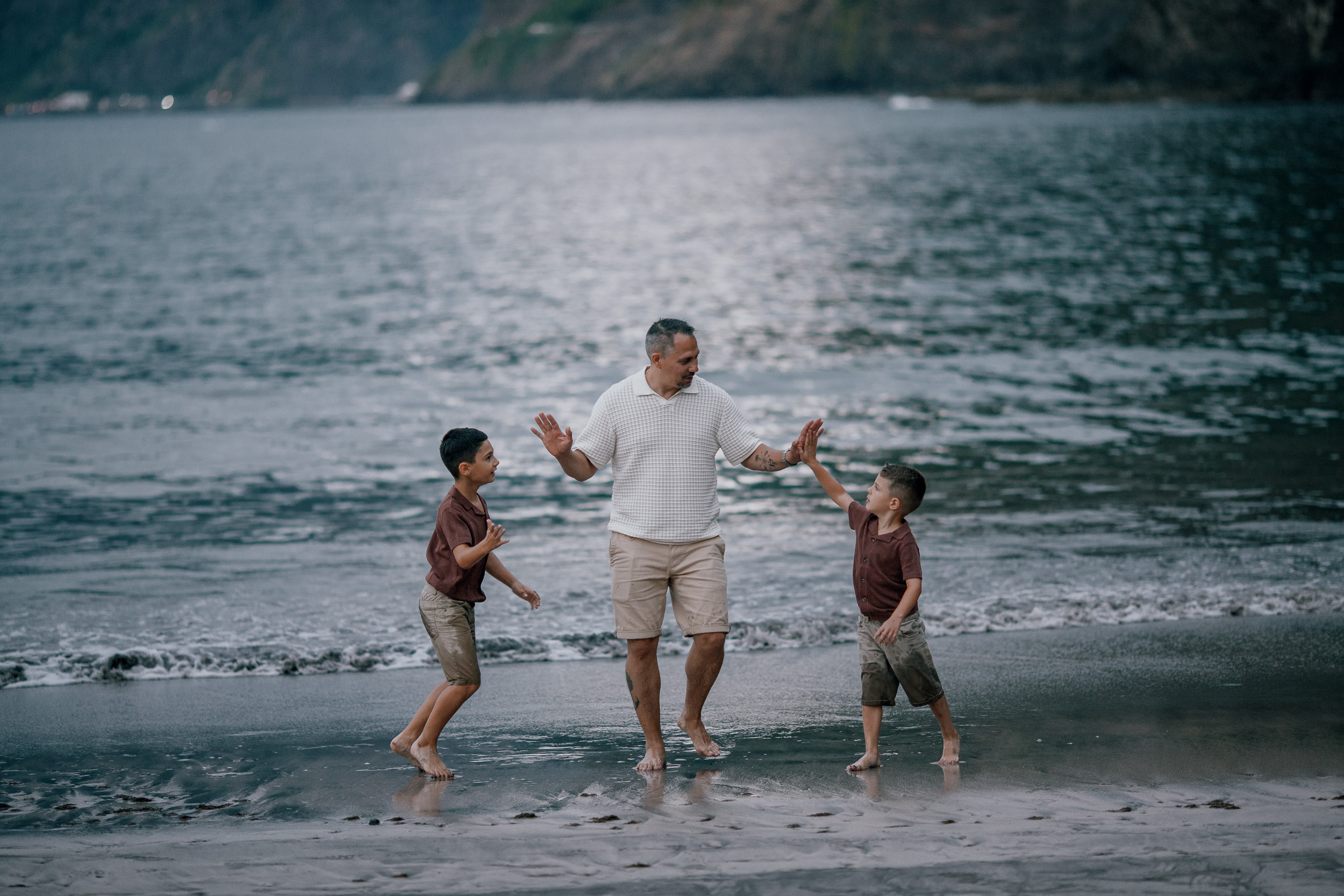 Father and sons splashing in the surf at dusk, Seixal, Madeira