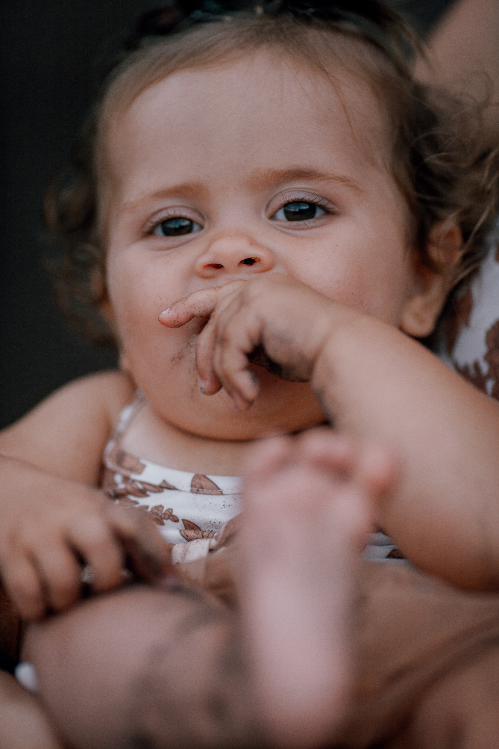 The baby girl chewing her fingers, feet in the air, close-up, Seixal, Madeira