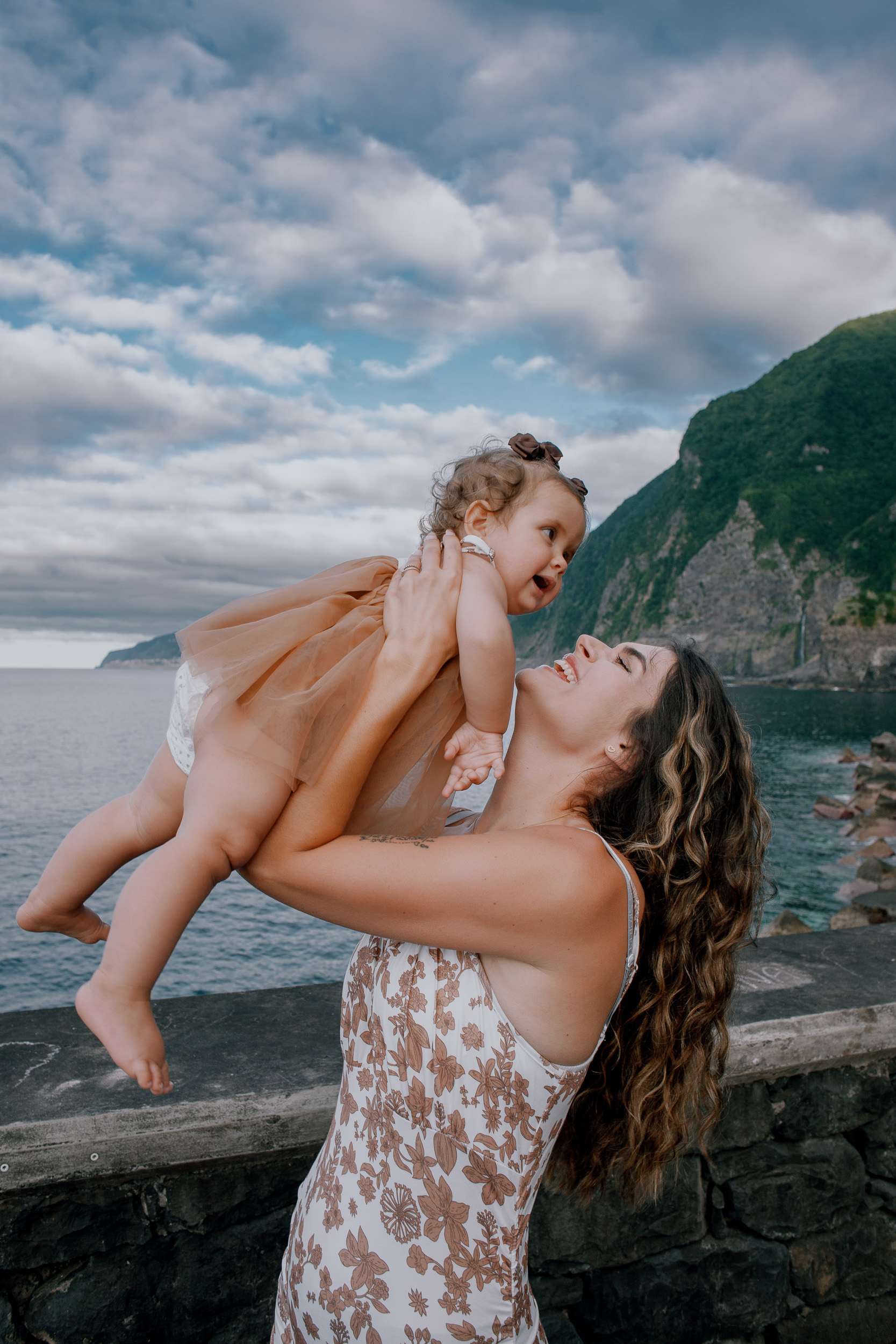 Mum lifting her daughter overhead laughing, Seixal Beach, Madeira