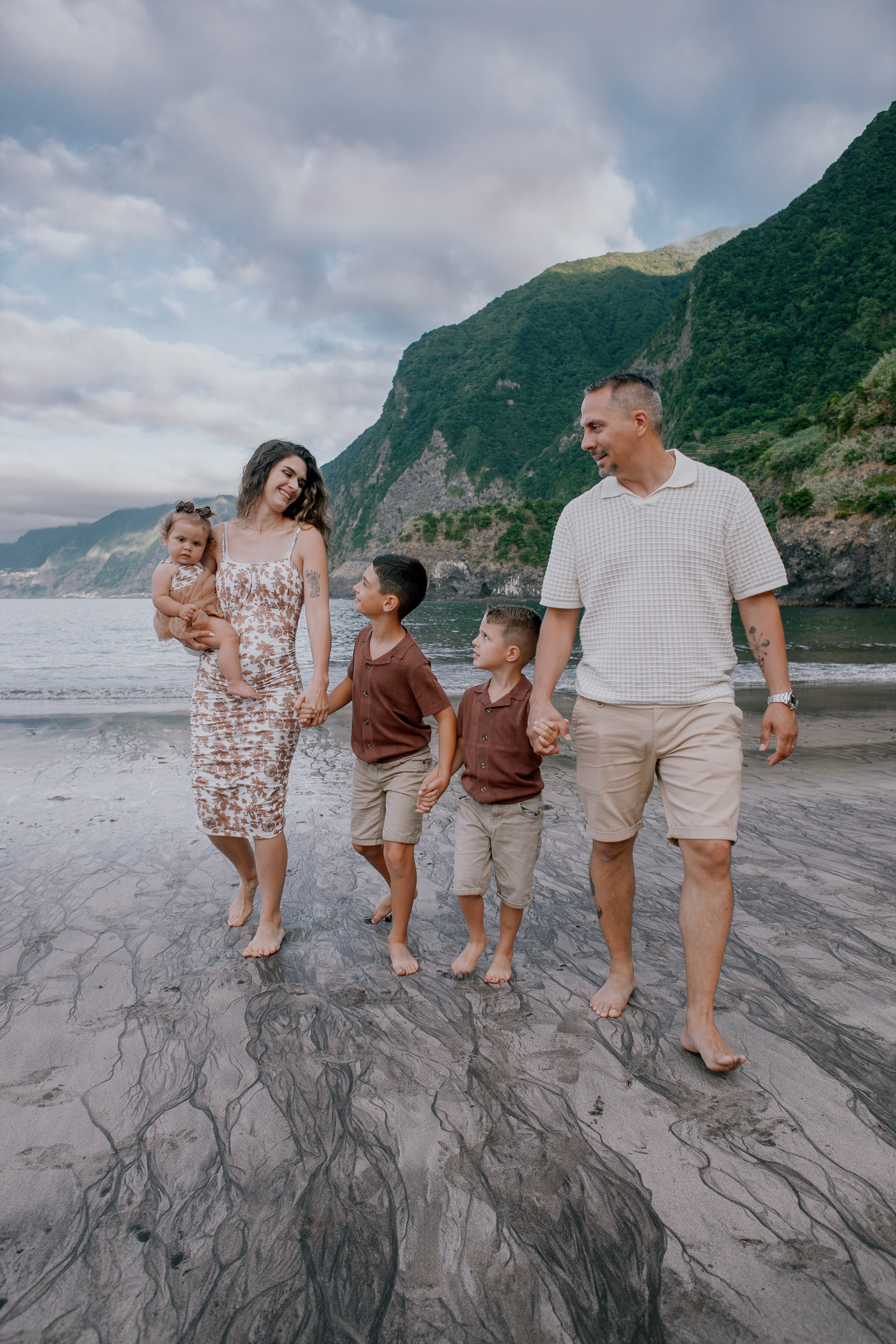 The family strolling the dark sand below the cliffs, Seixal Beach, Madeira