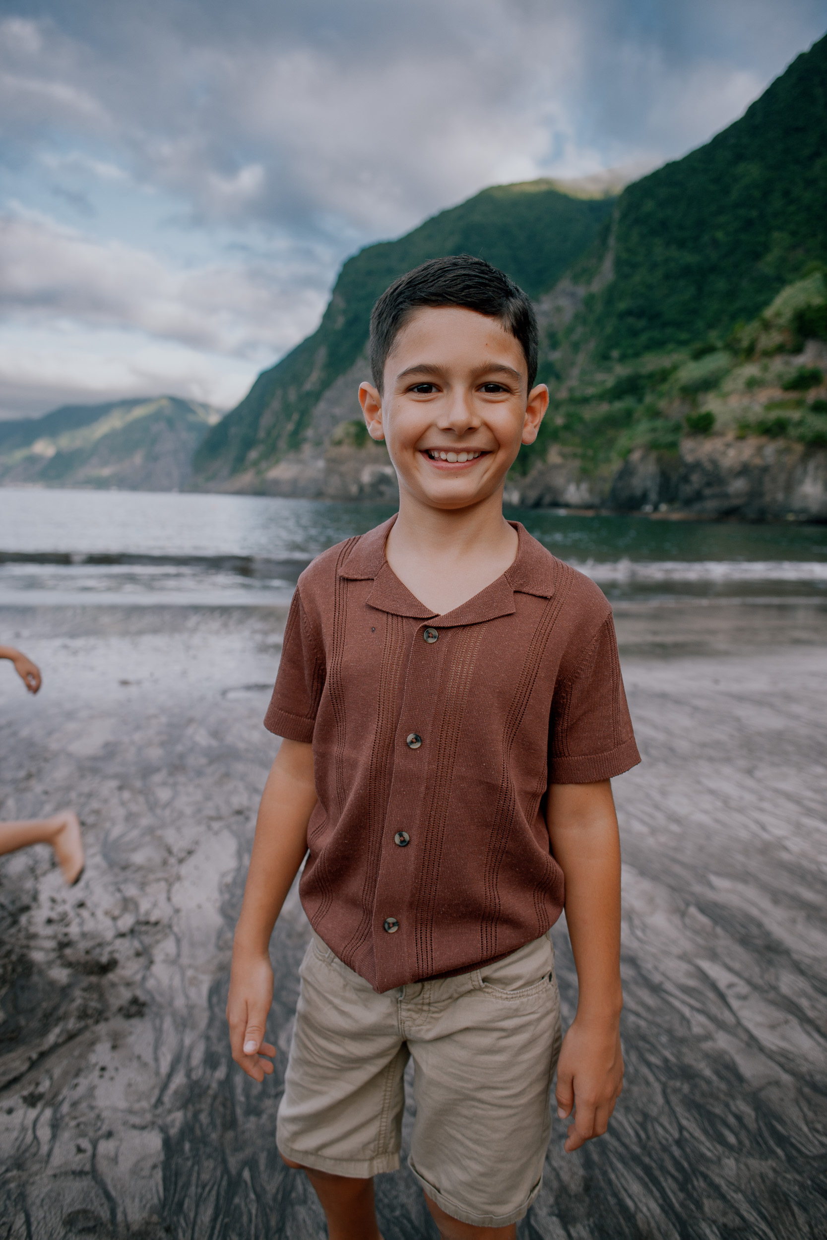 Portrait of the younger boy on the beach, brother running behind, Seixal, Madeira