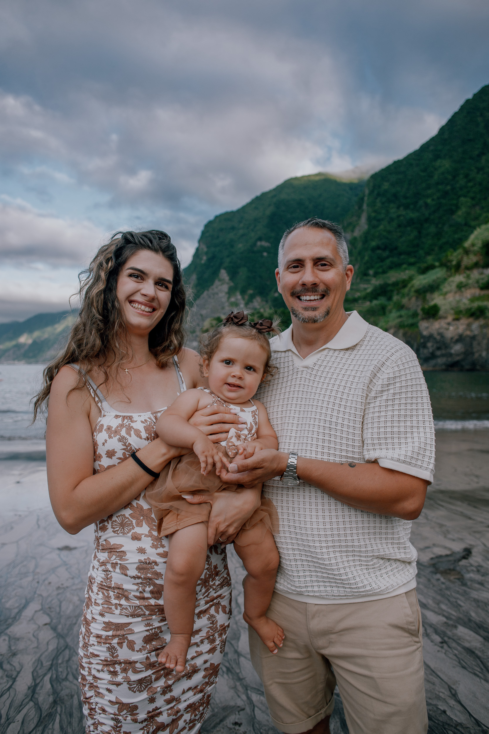 Mum and dad smiling with their daughter at the shore, Seixal, Madeira