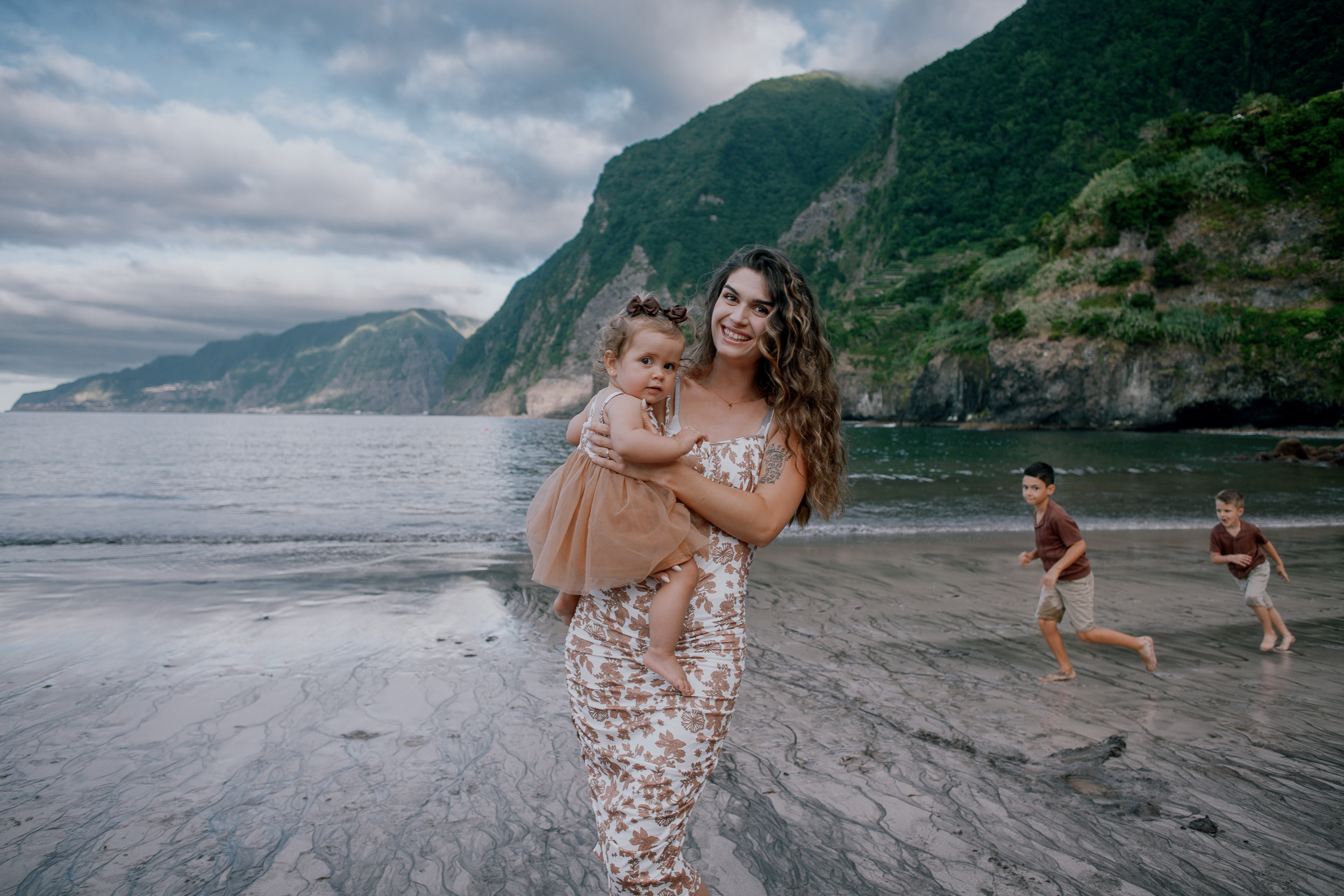 Mum and daughter at the shore, boys chasing waves behind, Seixal, Madeira