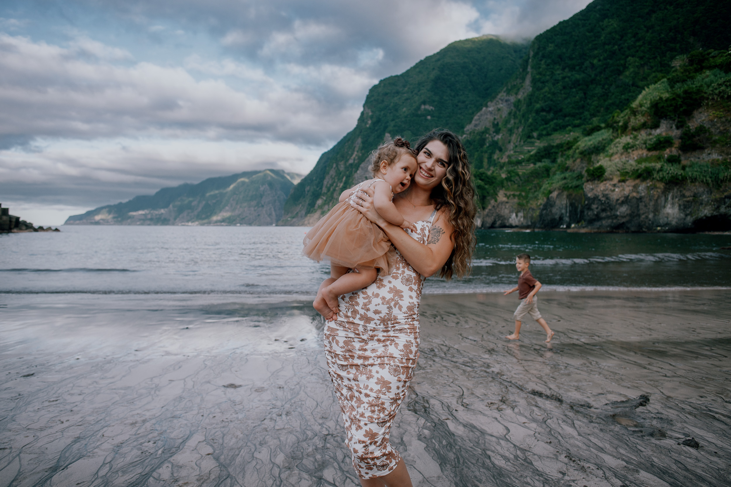 Mother smiling down at the baby stretching in her arms, Seixal, Madeira