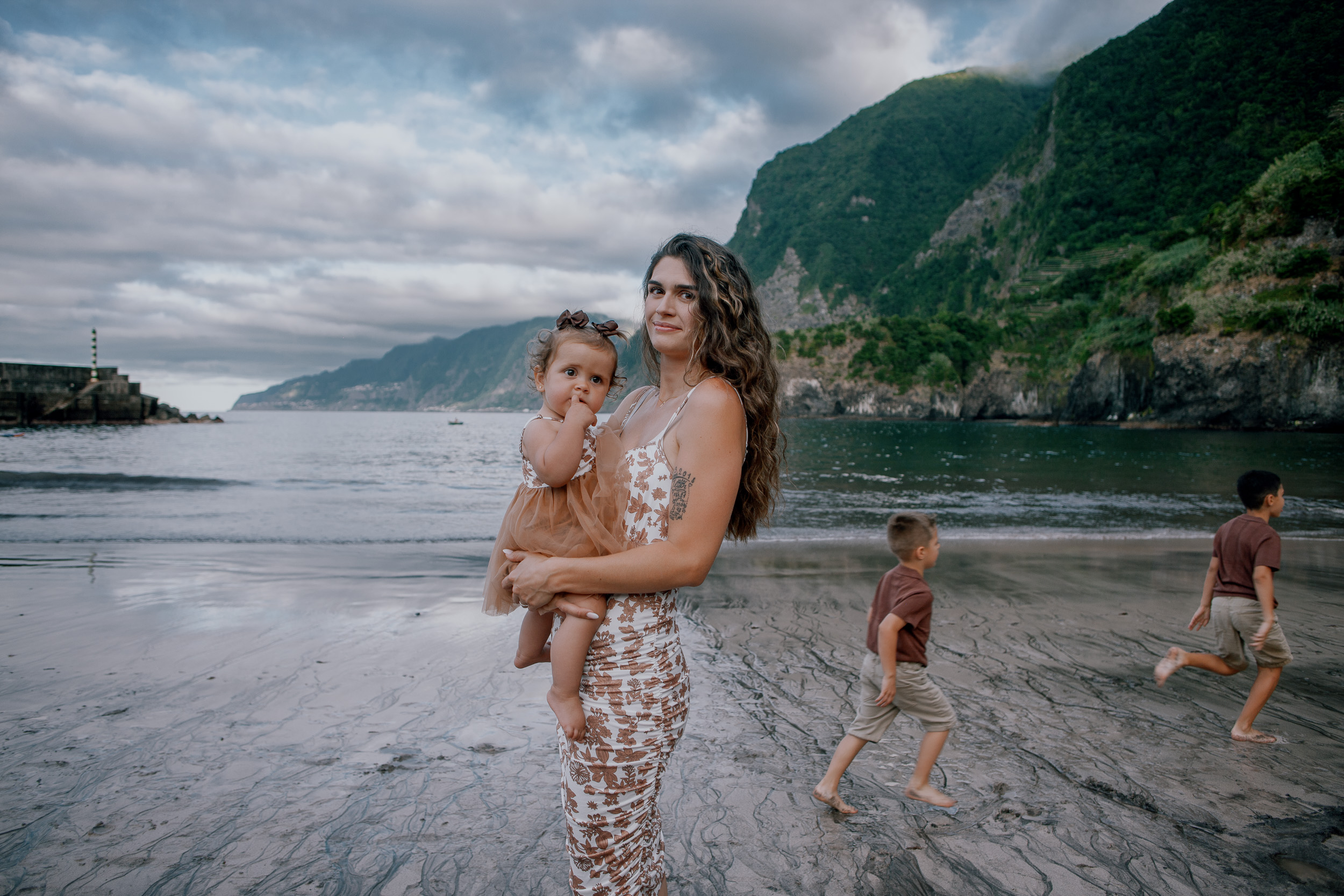 The family scattered across the wet sand playing, Seixal Beach, Madeira