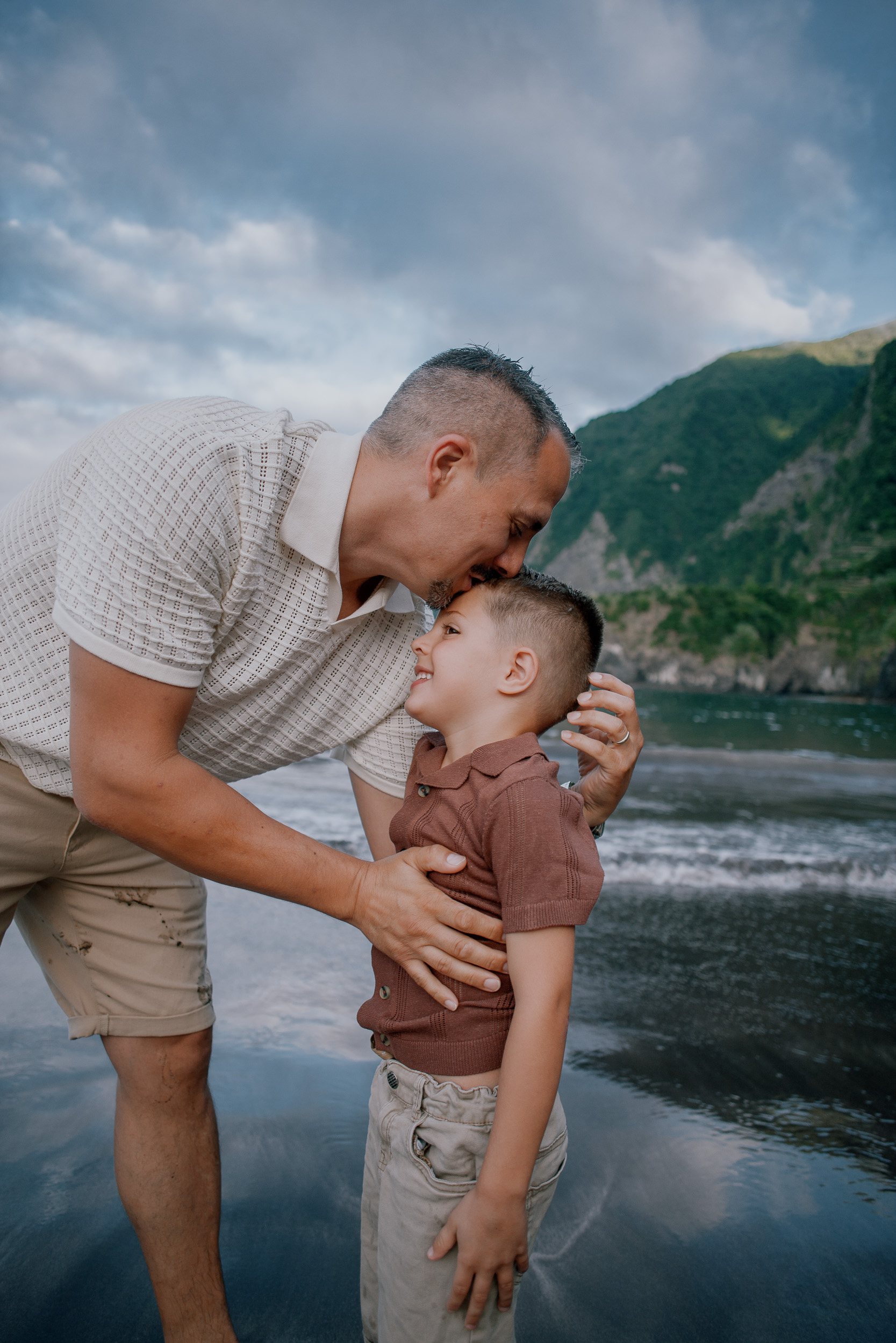 Father and son forehead to forehead at the shore, Seixal, Madeira