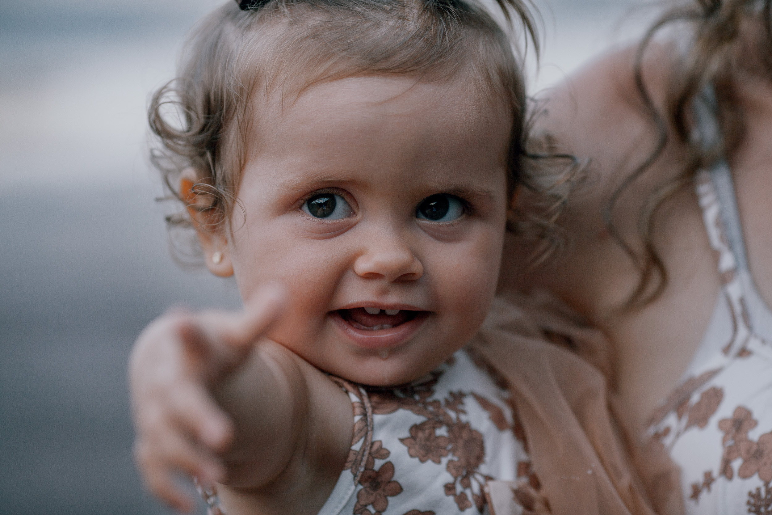 The baby girl pointing at the camera from mum's arms, Seixal, Madeira