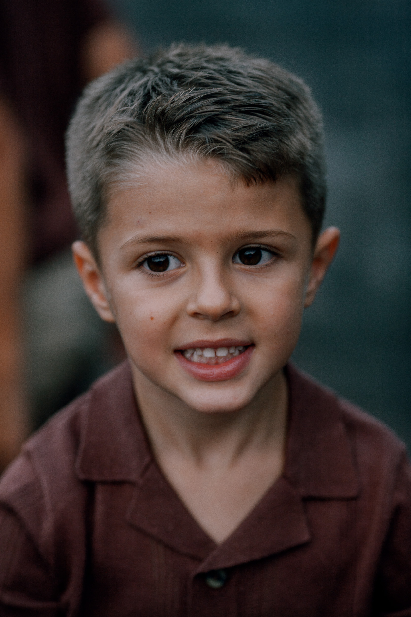 Portrait of the younger boy smiling, dark rocks behind, Seixal, Madeira
