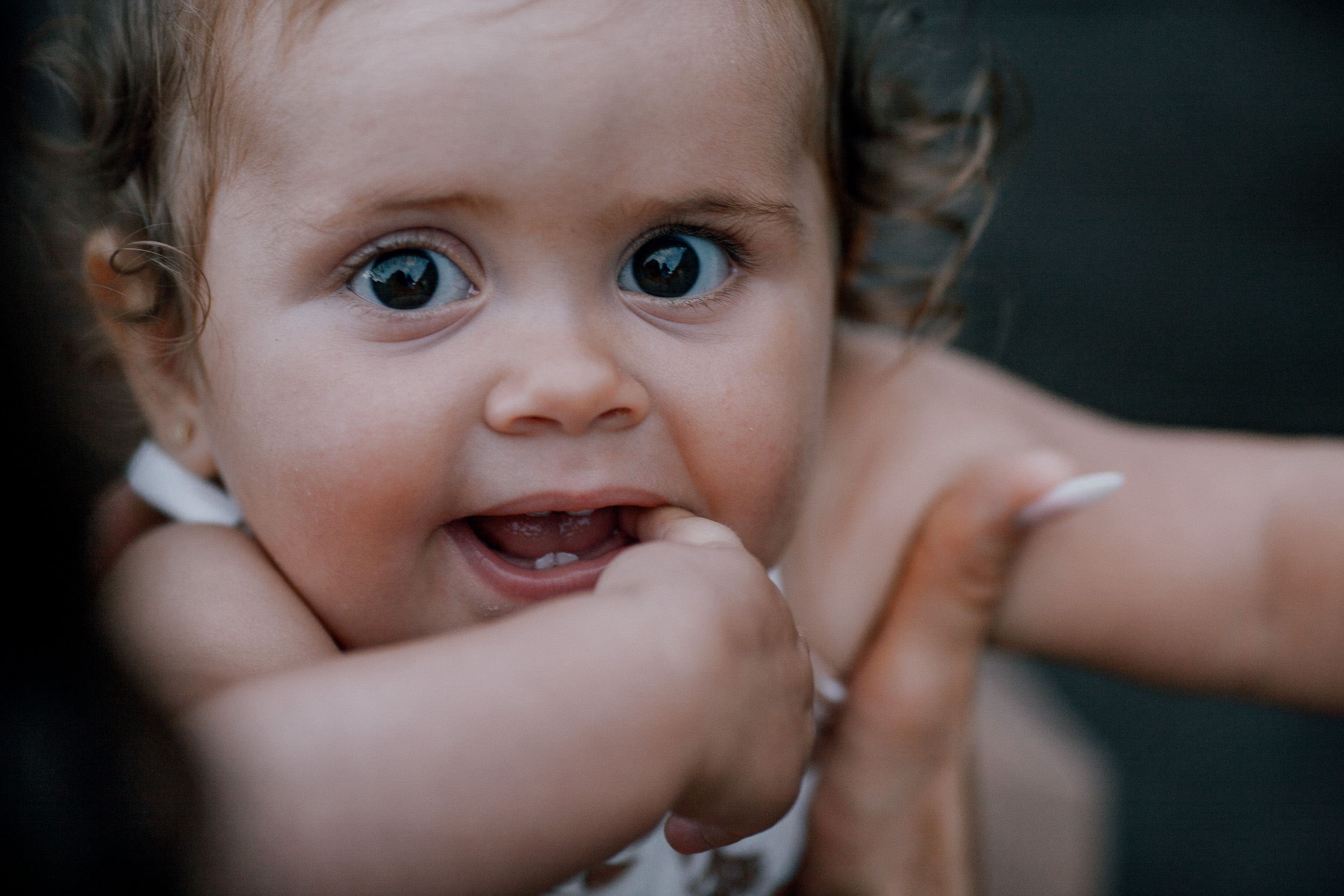 The baby girl wide-eyed with a hand in her mouth, close-up, Seixal, Madeira