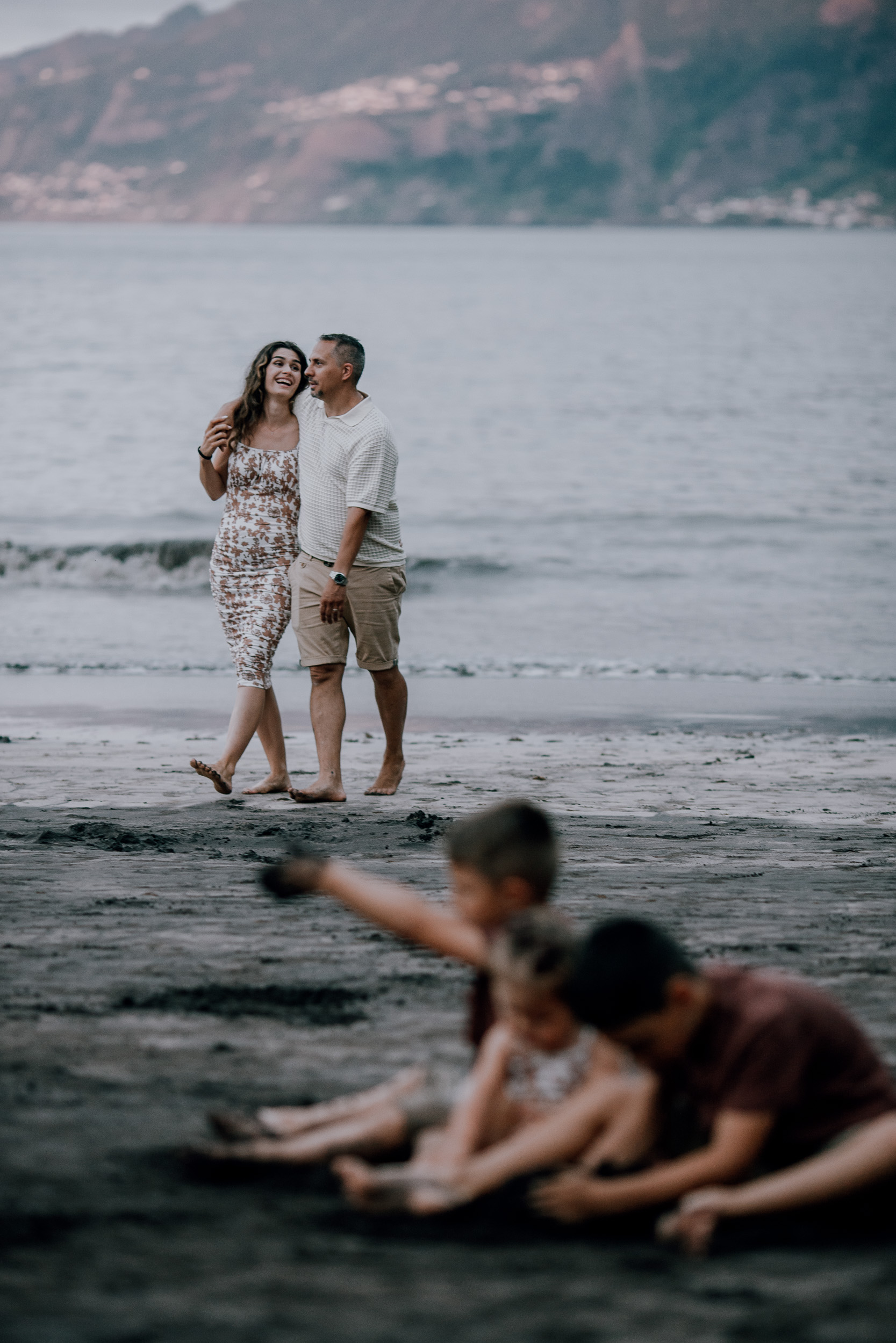 The parents laughing together at dusk, children in the sand, Seixal, Madeira