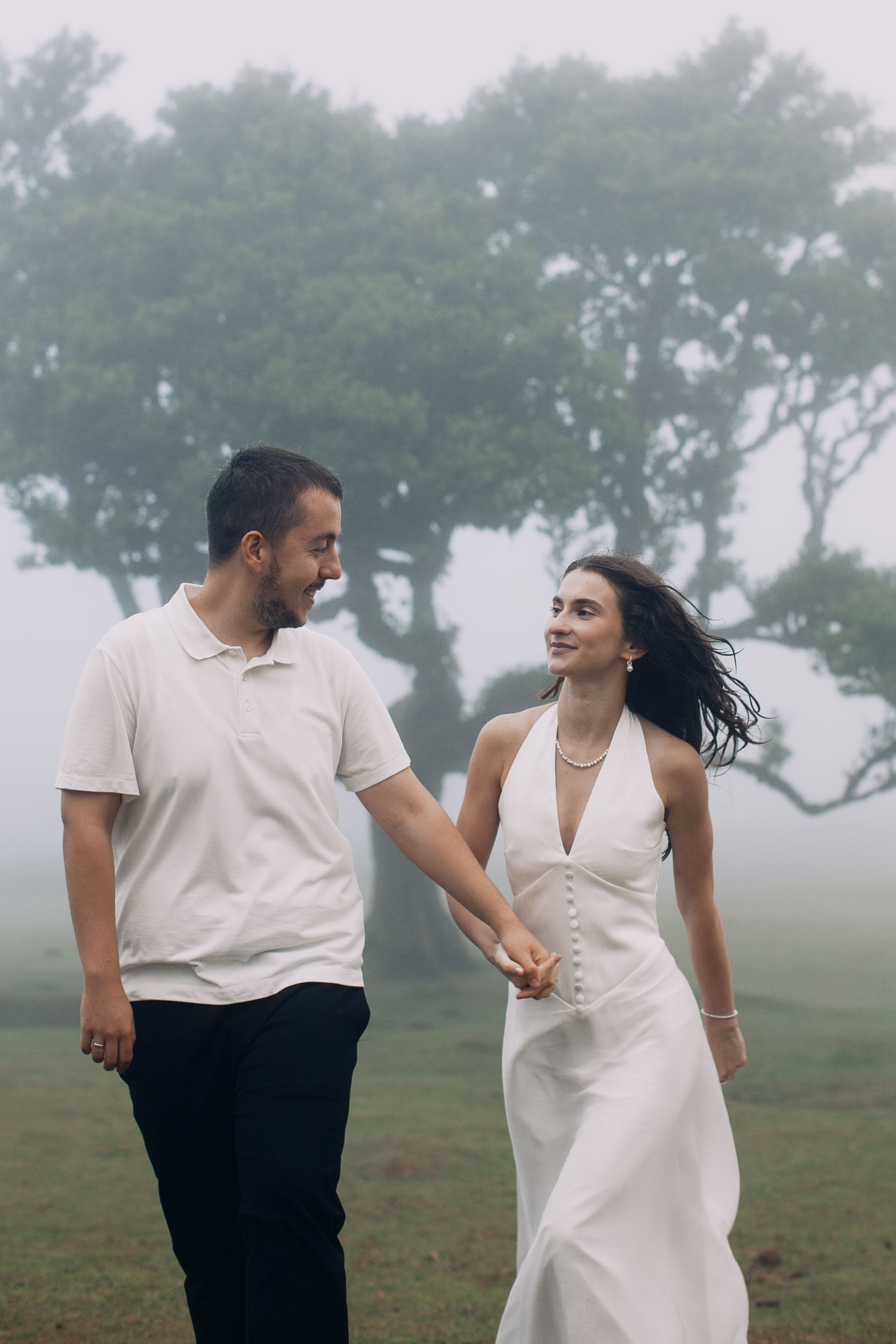 Couple walking close and laughing at each other in the fog of Fanal Forest, Madeira