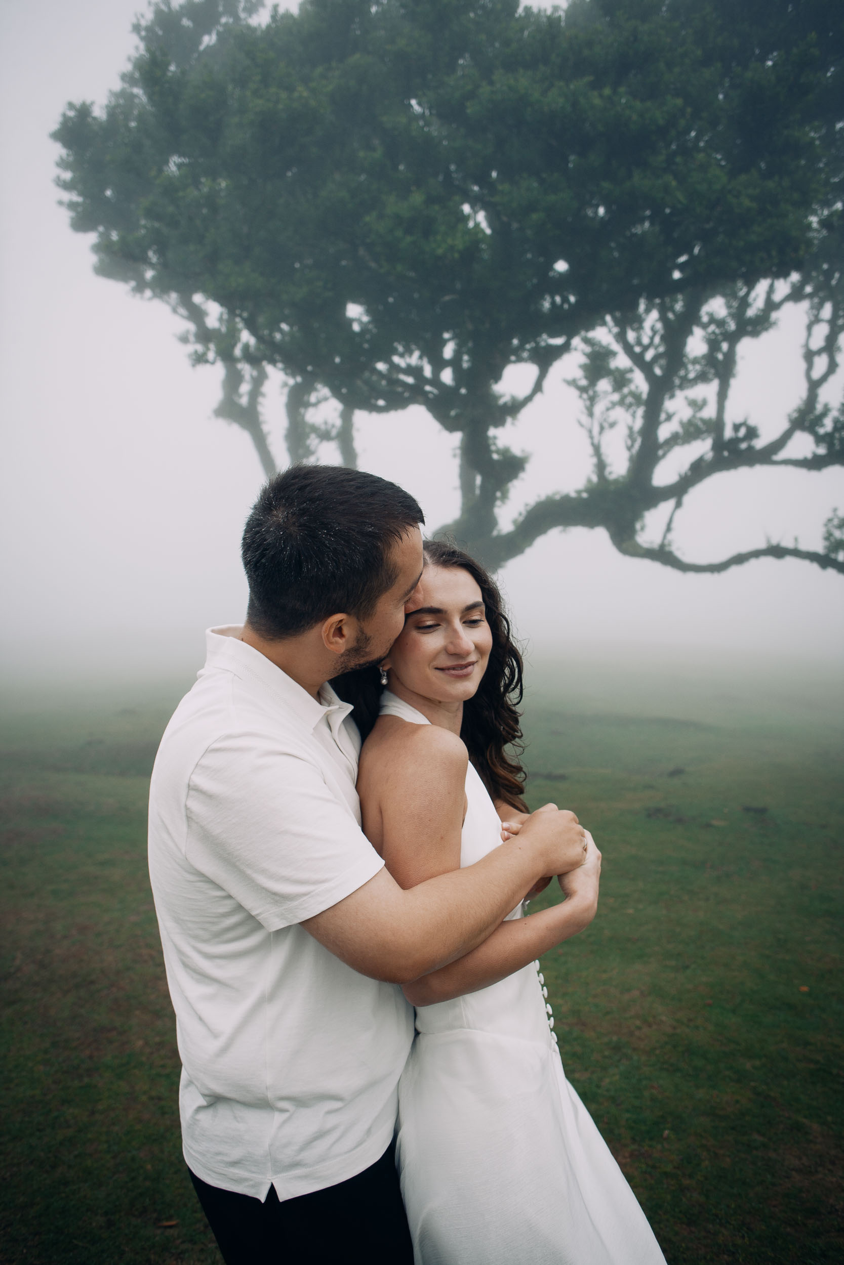 Couple close together in the fog of the laurel forest, her eyes closed, Fanal Forest, Madeira