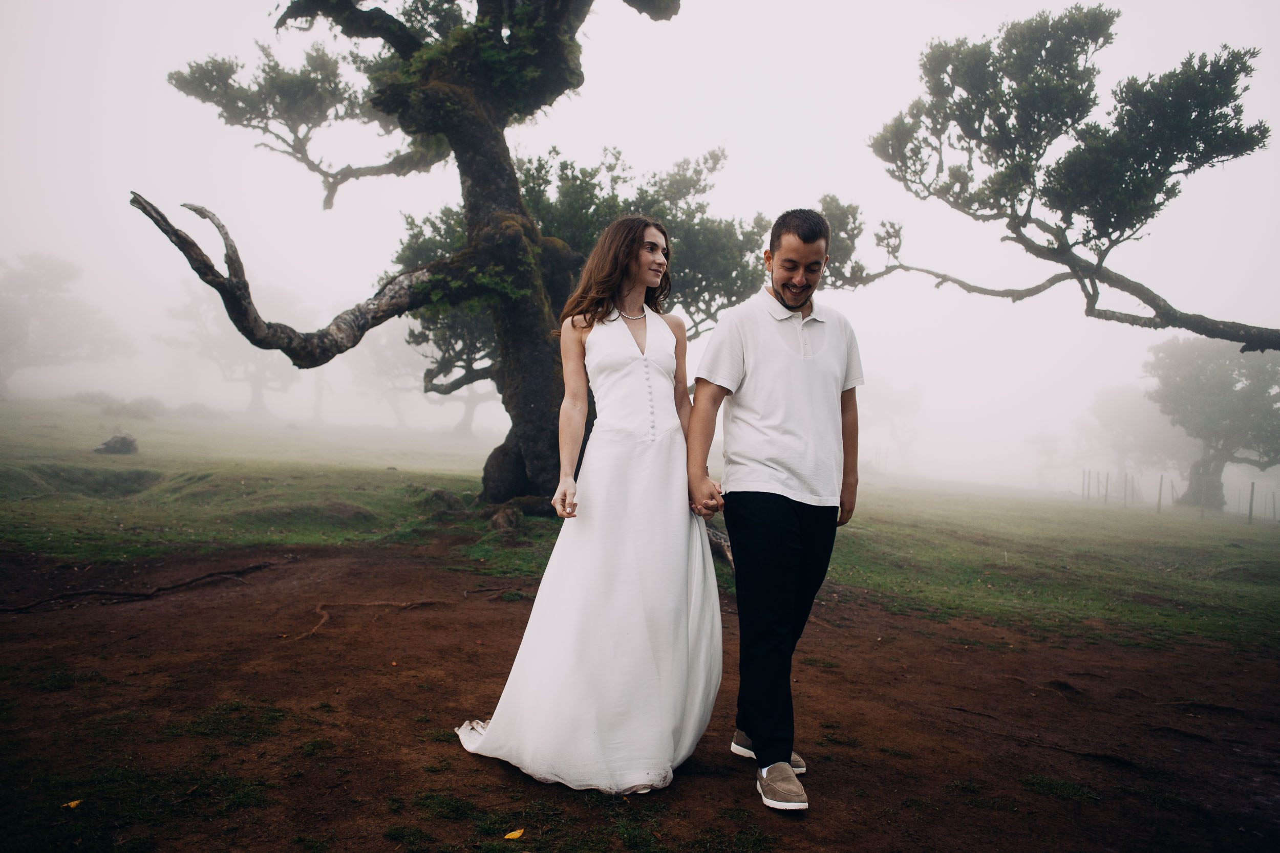 Couple walking a reddish earth path between laurel trees, Fanal Forest, Madeira