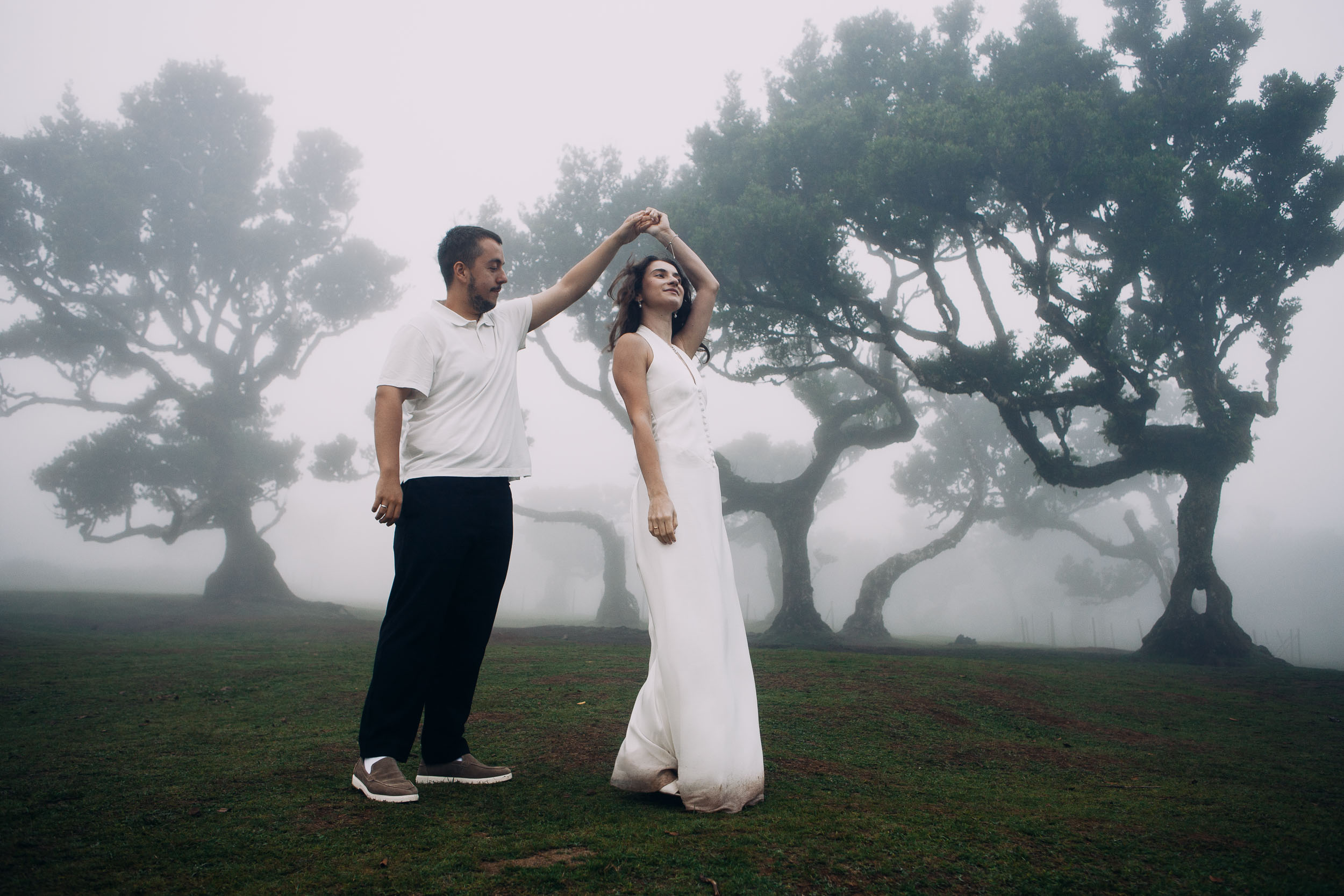 He turns her under his arm, she looks up smiling, mist across the plateau, Fanal Forest, Madeira