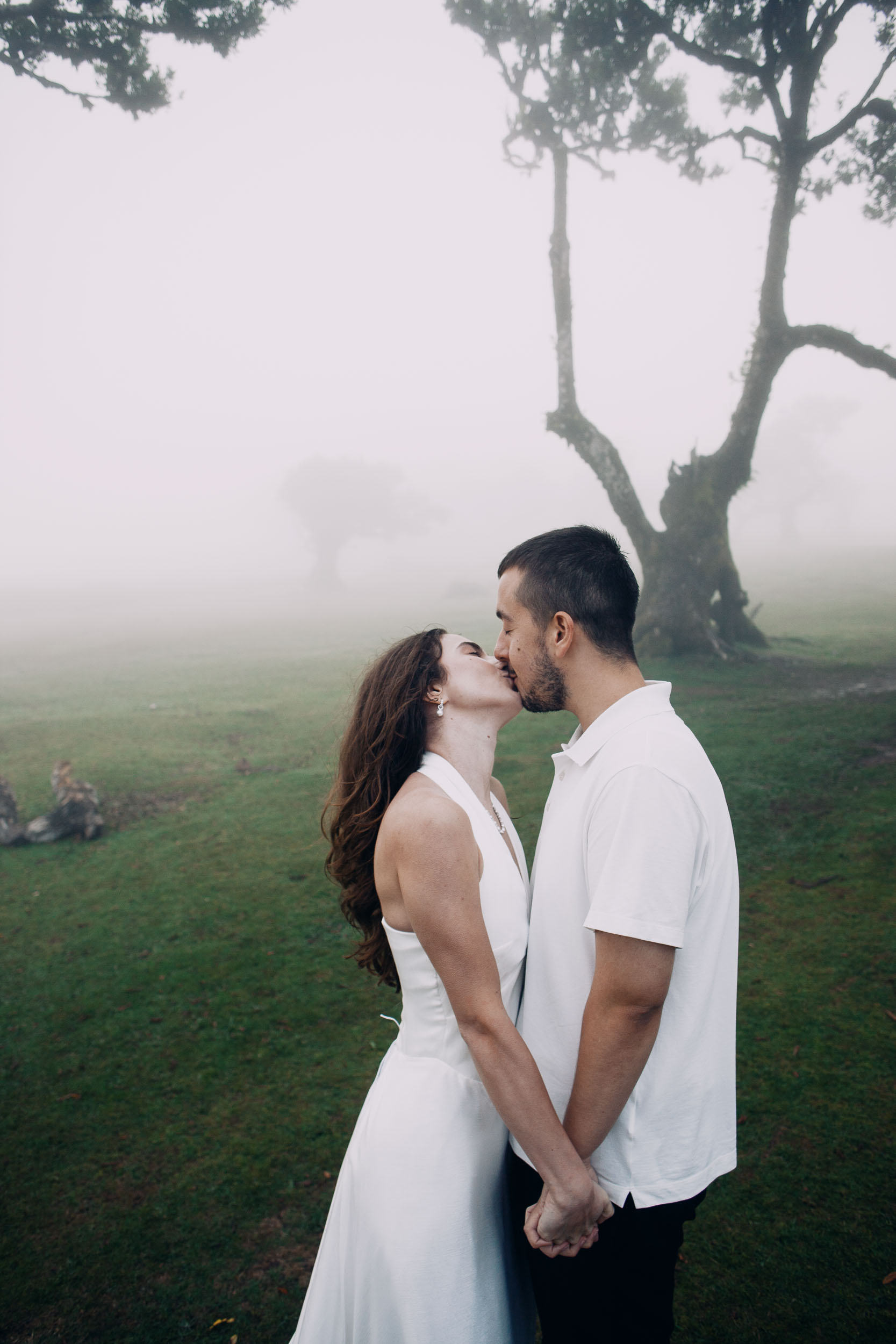 Couple kissing beside a laurel trunk in heavy fog, Fanal Forest, Madeira