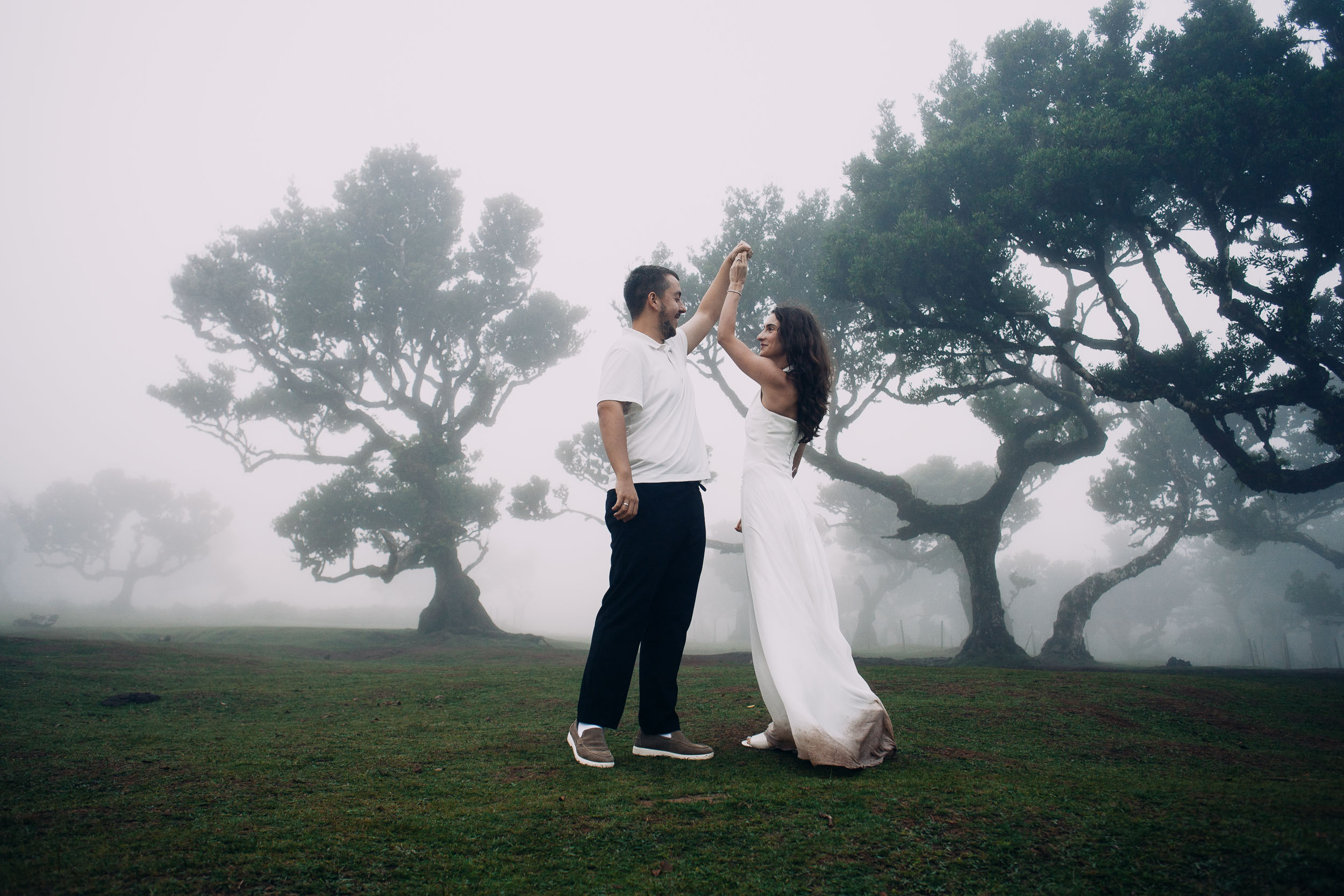 Couple dancing with joined hands raised, wet grass and laurels, Fanal Forest, Madeira