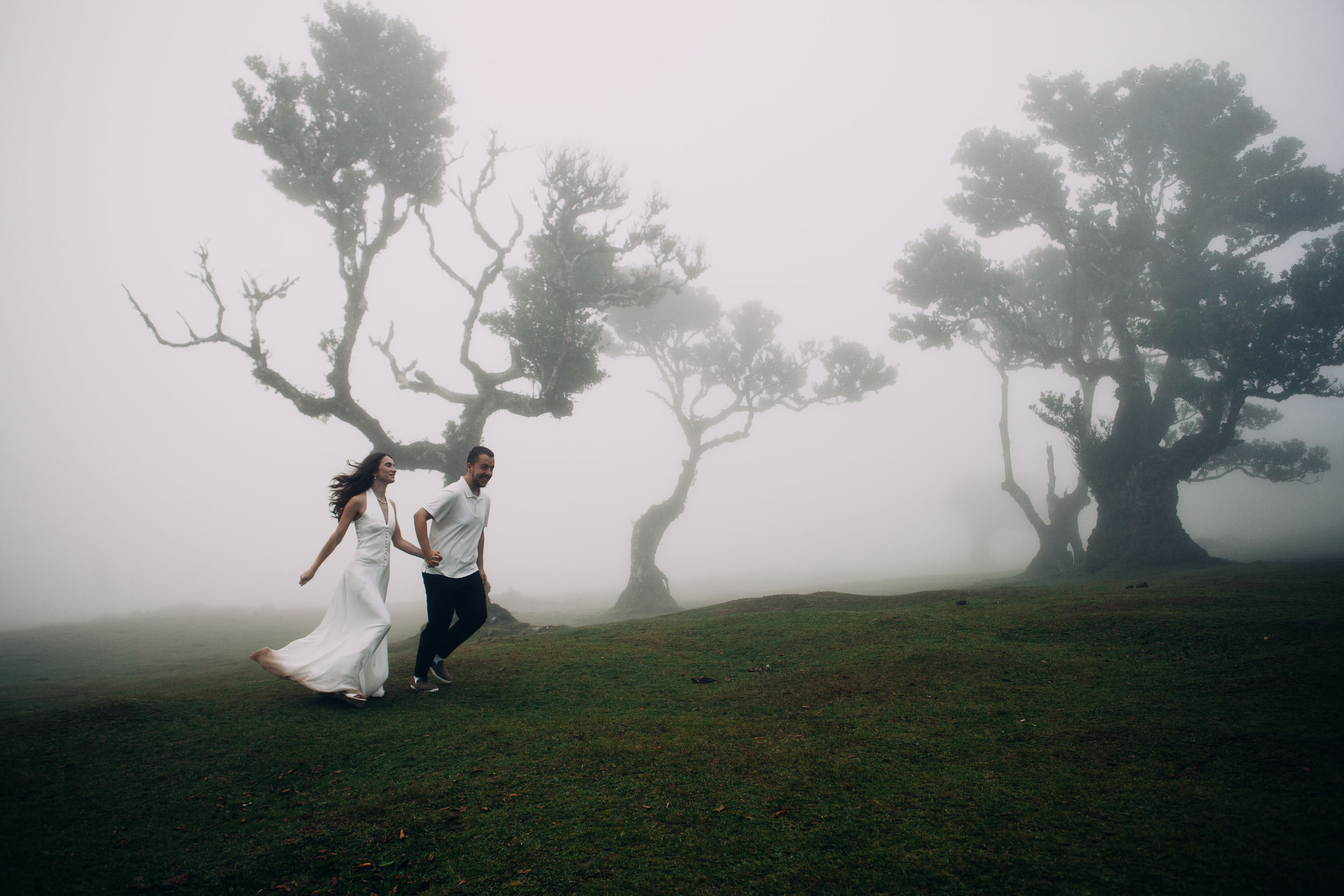 Couple running together across the grass of the Fanal plateau, Madeira
