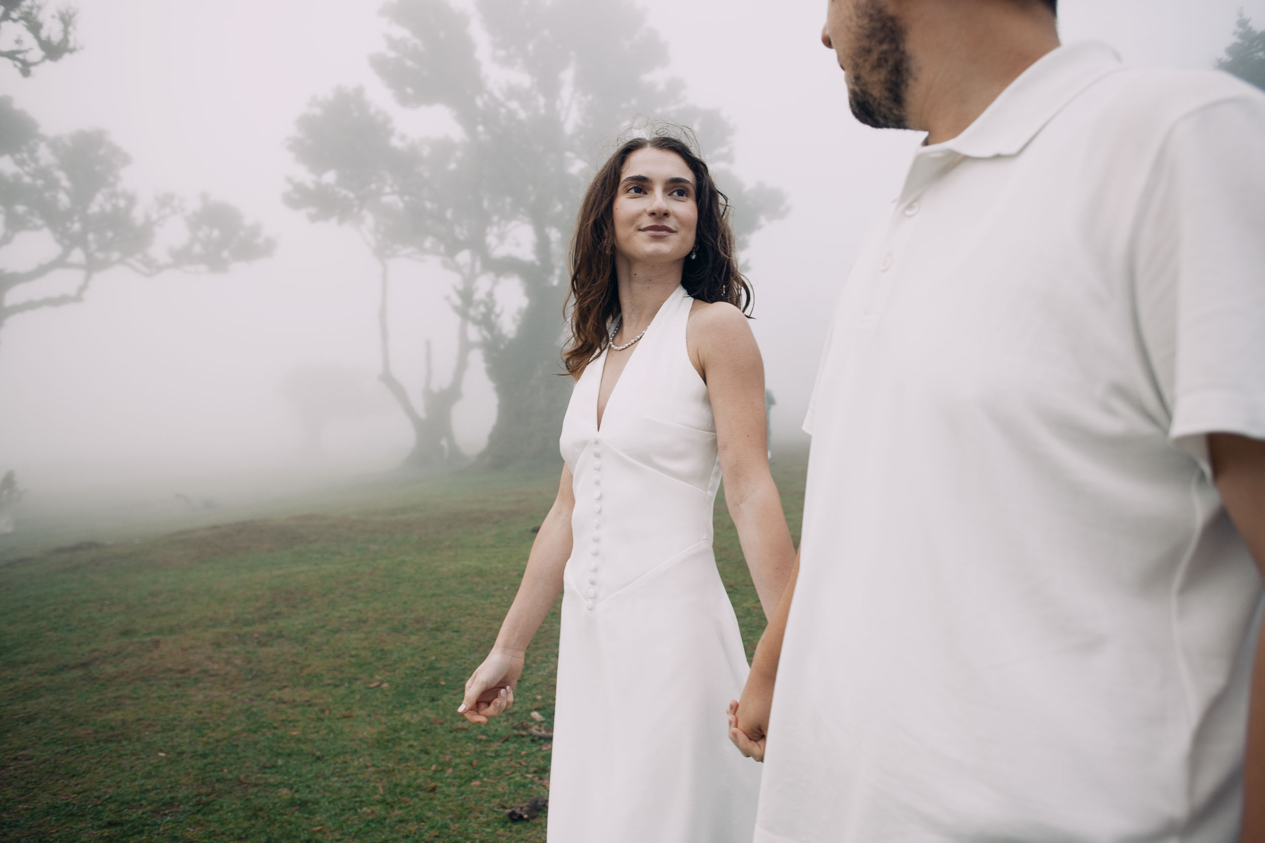Woman looking back over her shoulder as they walk on, laurels in cloud behind, Fanal Forest, Madeira