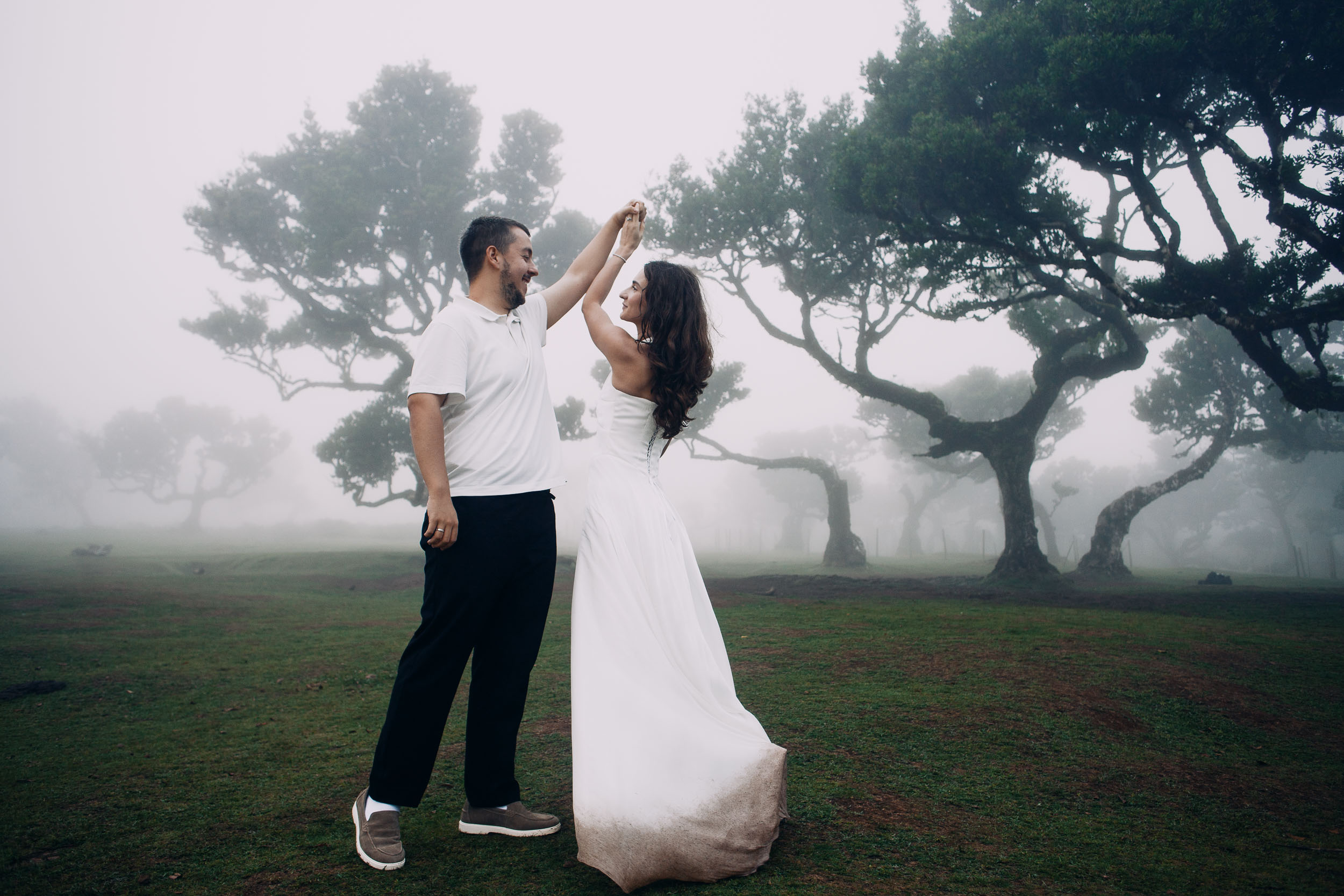 Wide frame of the couple dancing between laurel trees, Fanal Forest, Madeira