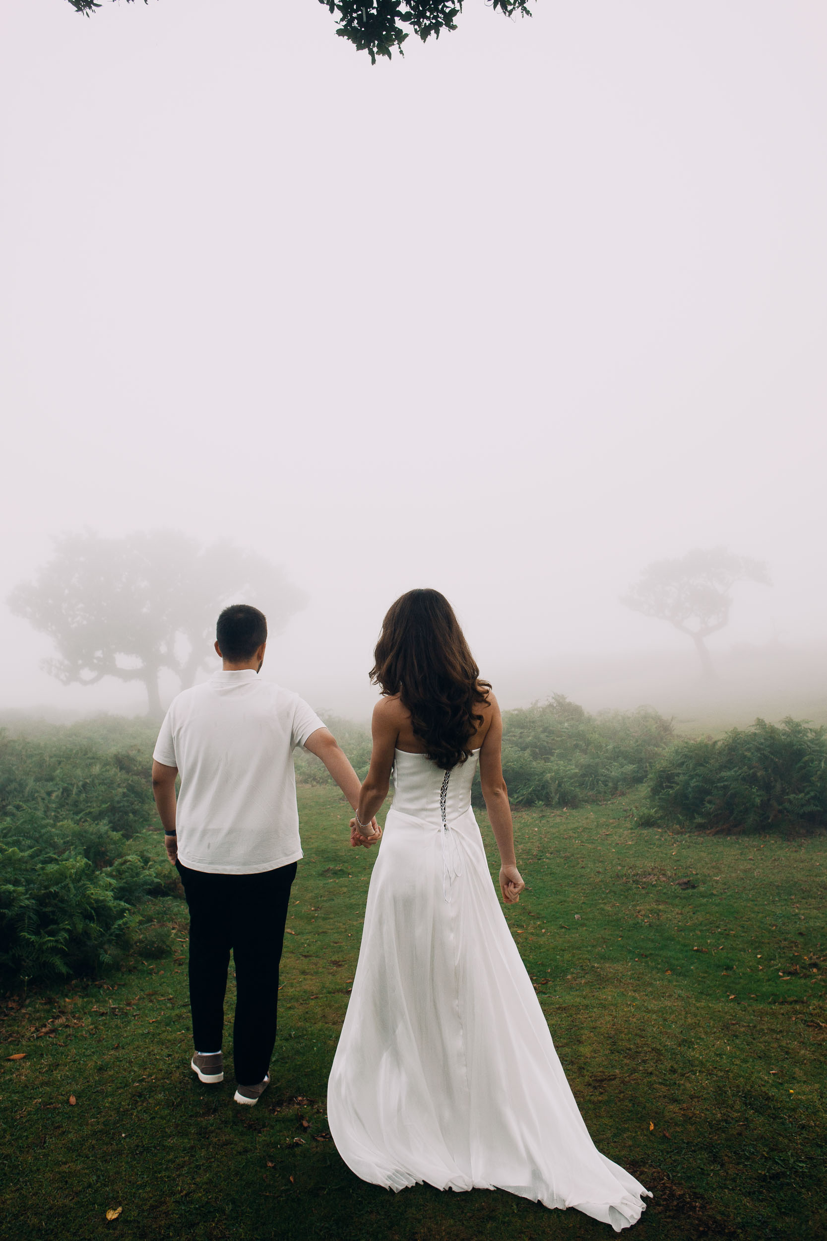Couple walking away hand in hand into the mist, Fanal Forest, Madeira