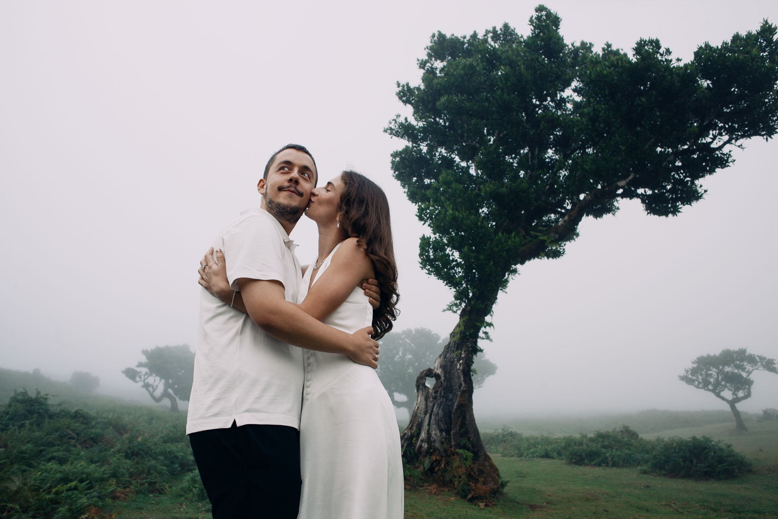 She kisses his cheek under the branches of an old laurel, Fanal Forest, Madeira